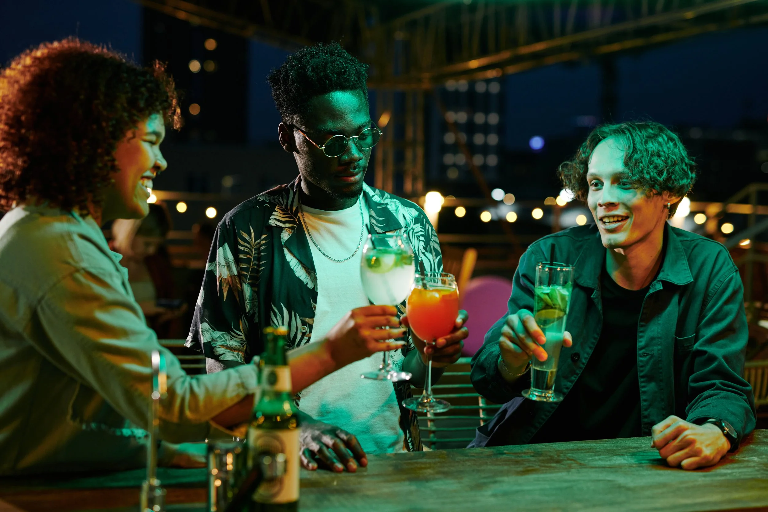 thre young people enjoying a drink out in the evening at a bar