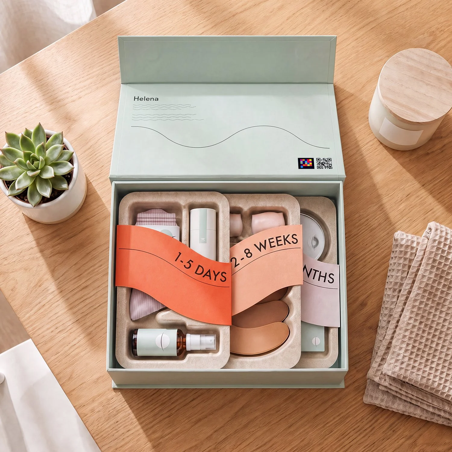 A box of medical products for the first 8 weeks of pregnancy, labeled with timeframes: 1-5 days, 2-8 weeks, months. The box contains various small bottles, tablets, and medications. The scene is on a wooden table with a potted succulent plant, a small white container, and a folded hand towel nearby.
