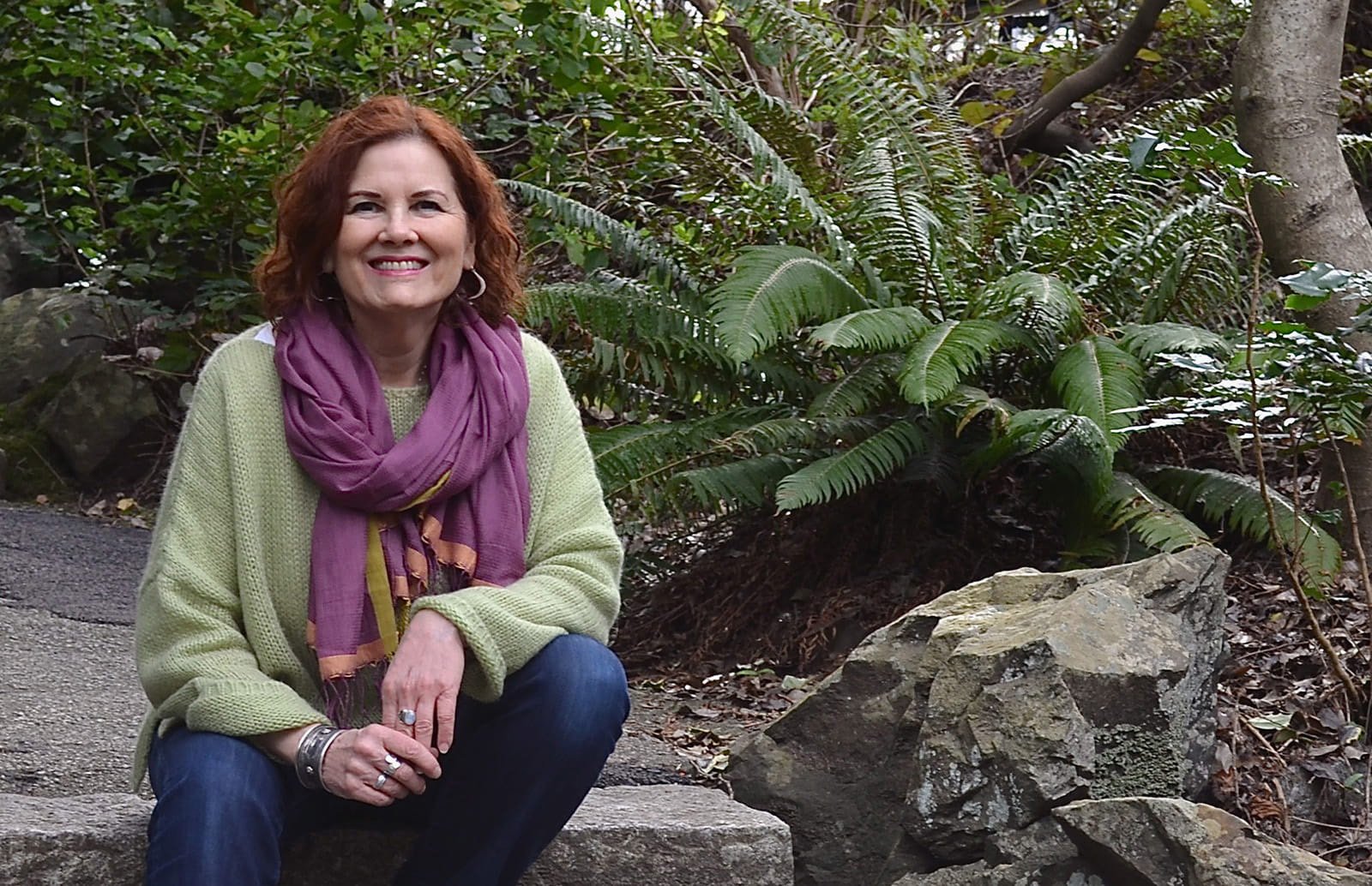 Photo of woman sitting on stone steps surrounded by greenery