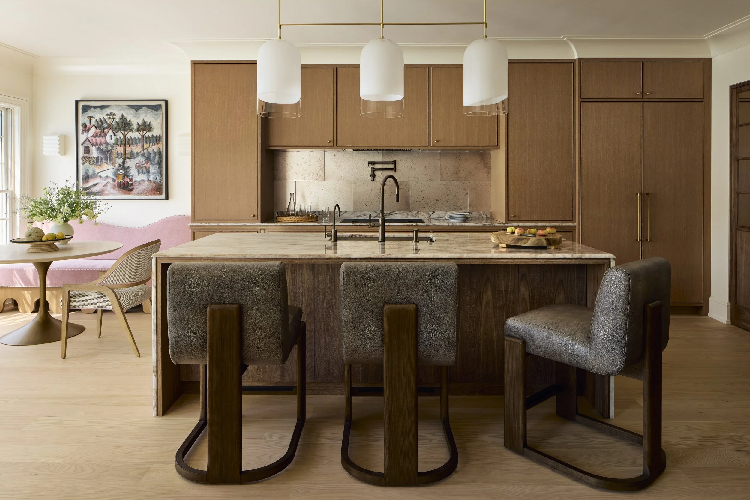 The island in the kitchen pairs a beautiful and hardwearing natural quartzite counter with cerused walnut millwork, which complements the warm cerused white oak of the rest of the kitchen. The backsplash was tiled in a large format antiqued glass til