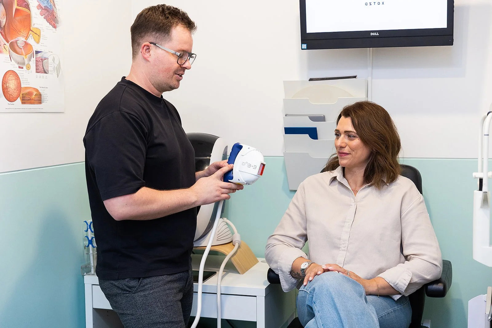 A doctor showing a medical device to a woman patient in a clinic.