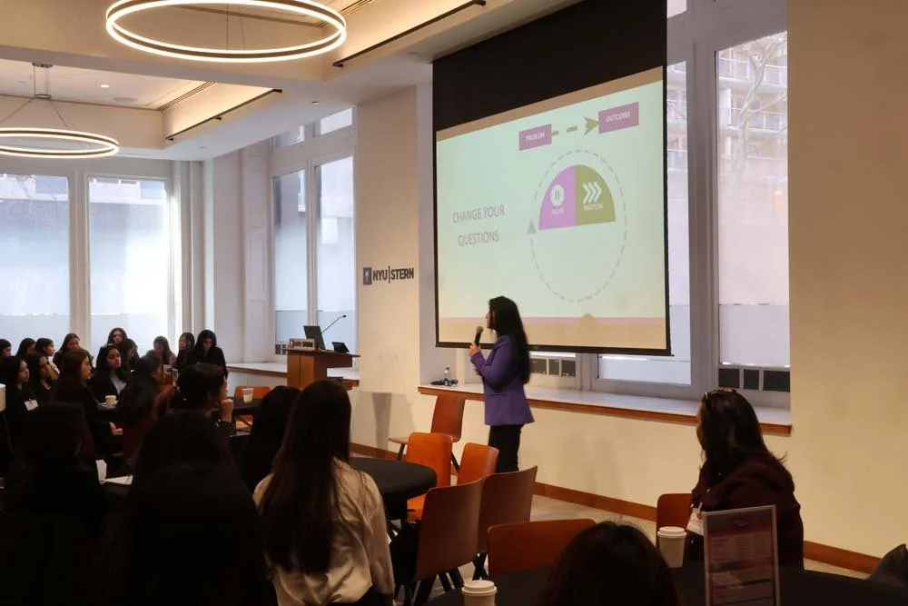 A woman giving a presentation to an audience in a classroom or conference room at NYU Stern.