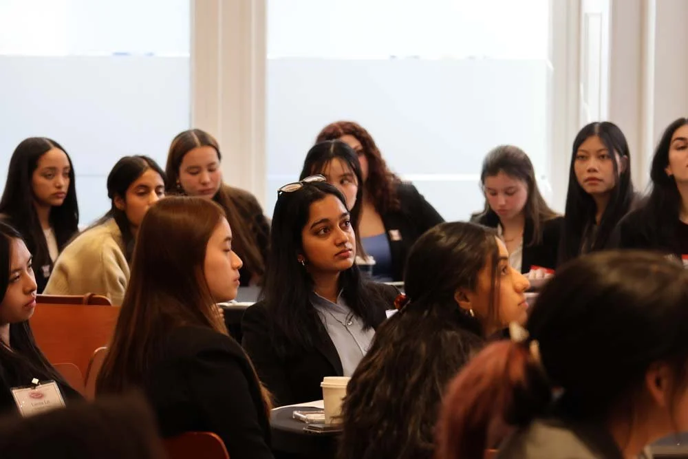 A group of women and girls attending a conference or seminar, seated and listening attentively.
