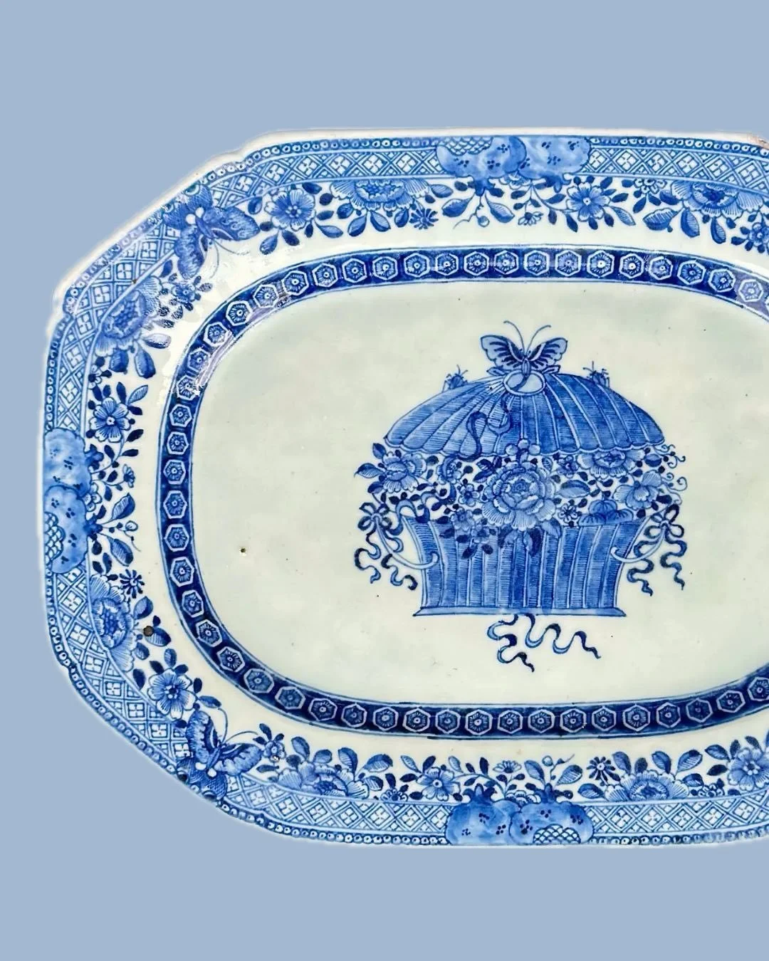A close look at a Qing Dynasty Chinese export platter, circa 1800. Hand-painted, the basket overflows with flowers while tiny insects perch atop the lid. The subtle variation in the cobalt&mdash;from deep inky blue to soft washes - brings the design 