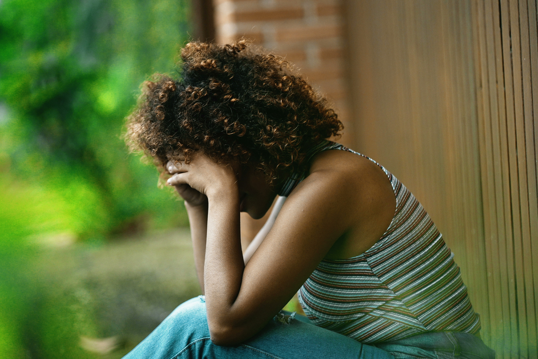 A woman with curly hair buries her head in her hands.