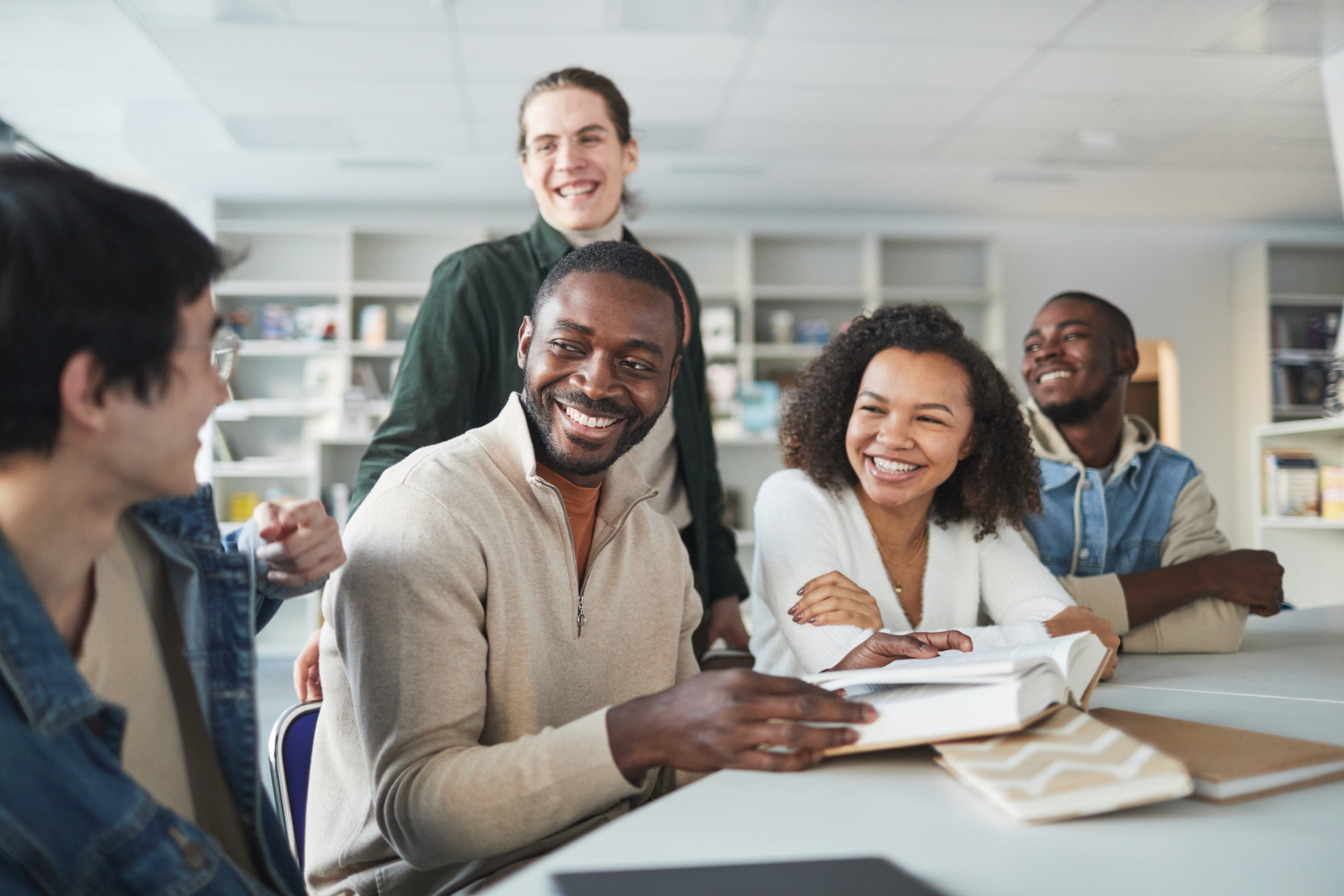 A group of people sit around a table smiling at each other.