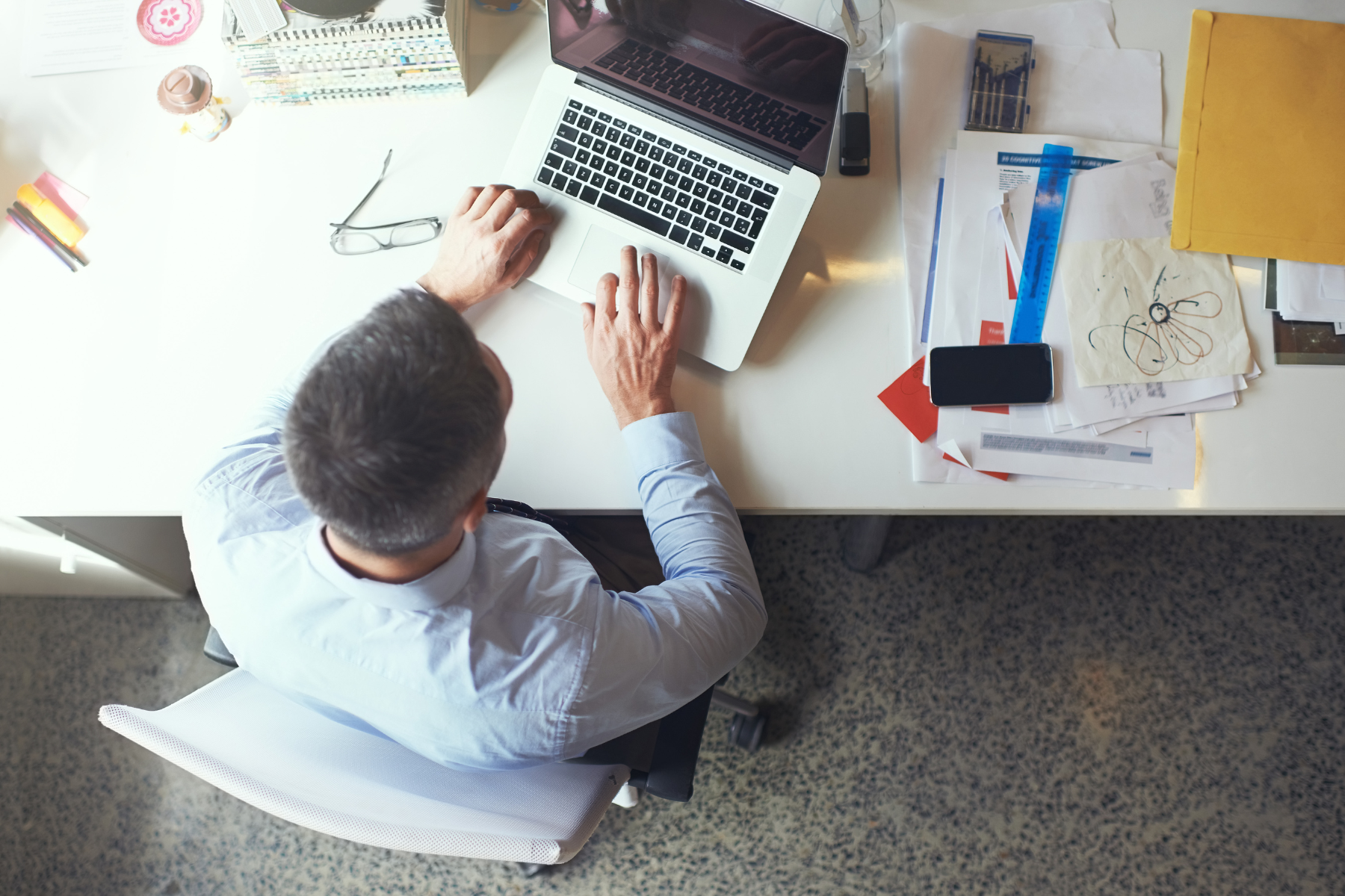 An overhead photo of a man at a messy desk, working