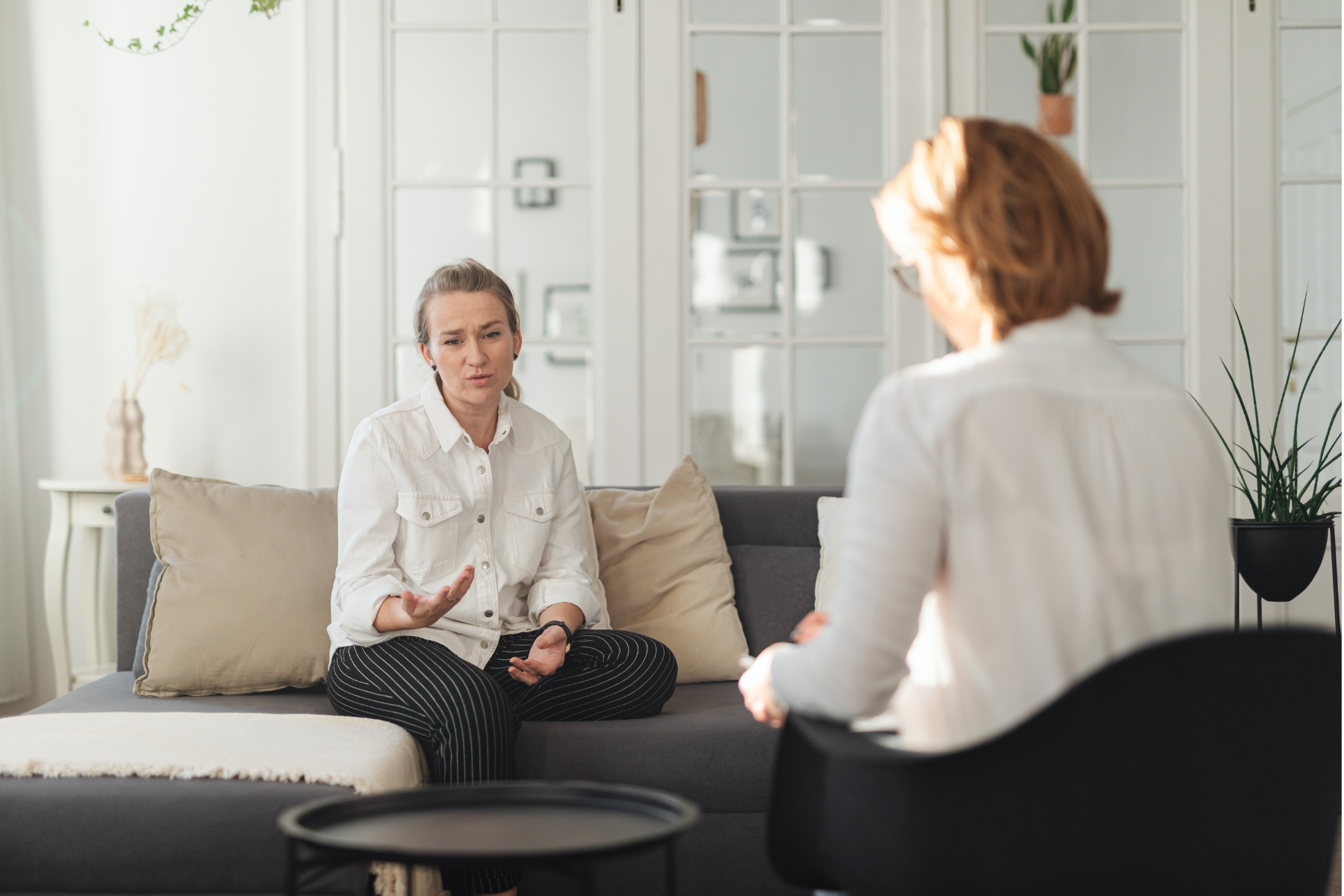A woman sits on a couch, talking to her therapist