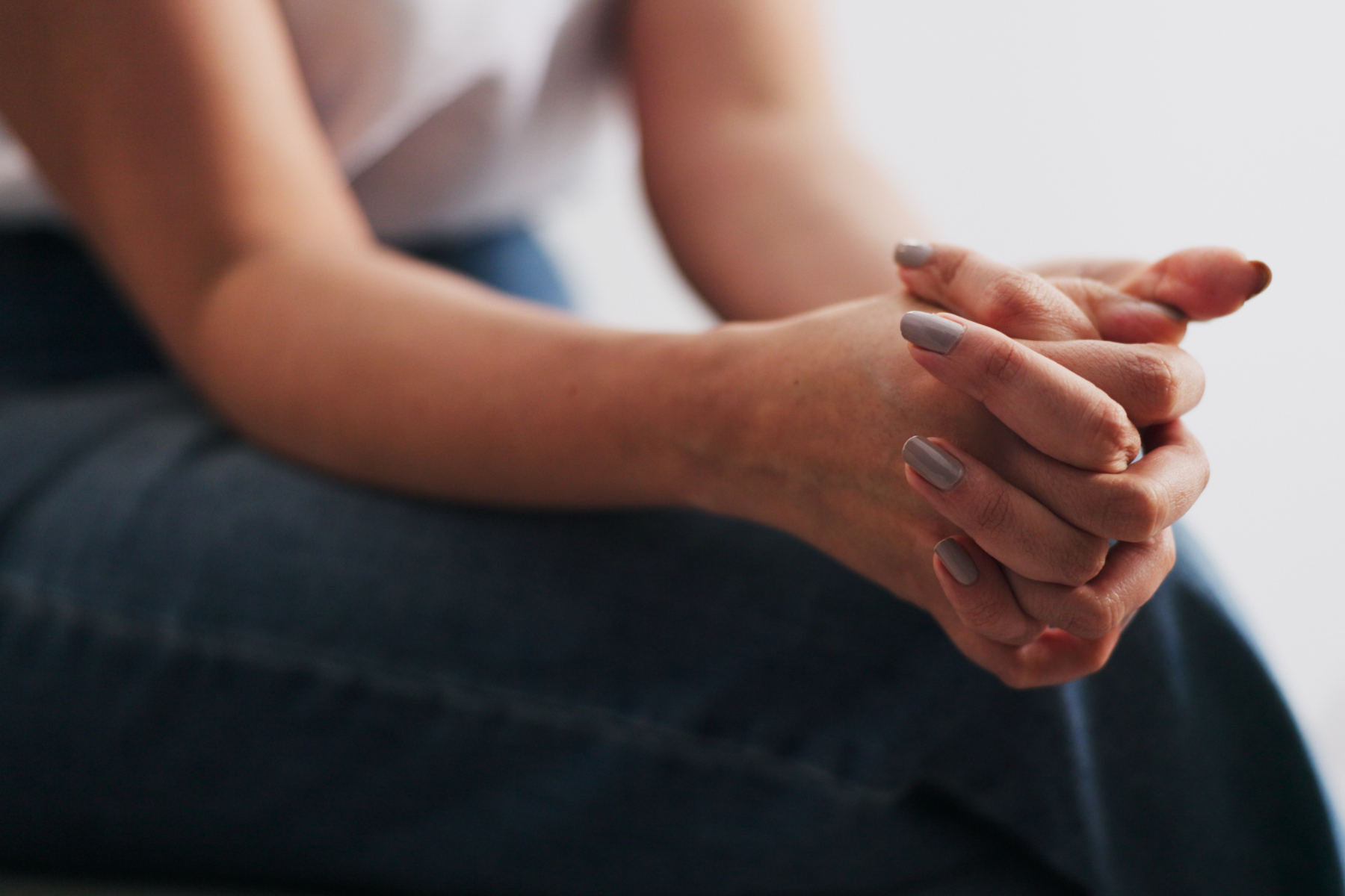 A woman clasps her hands atop her legs