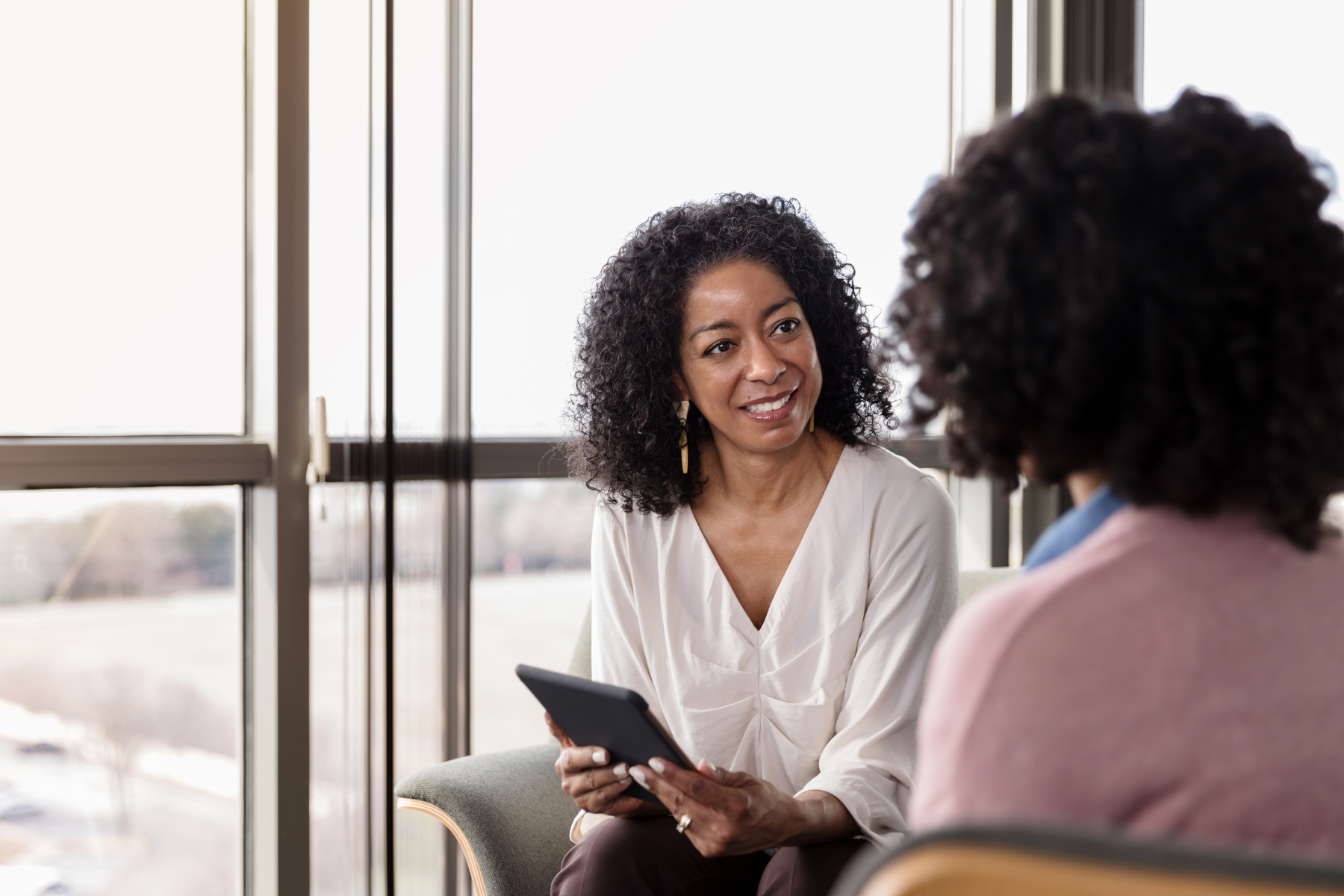 A therapist listens to her client, taking notes on a tablet