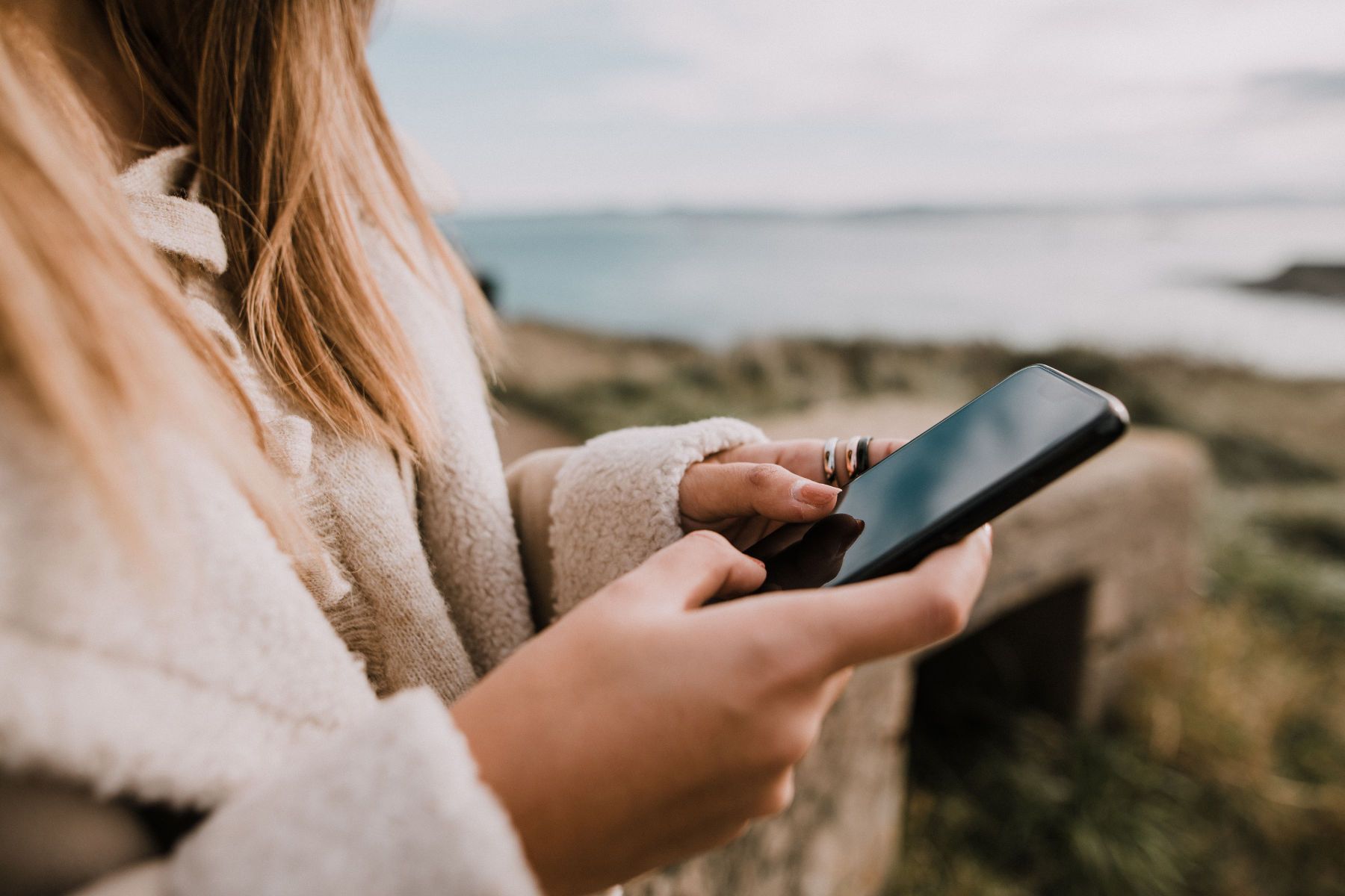 A close-up image of a woman typing on her phone
