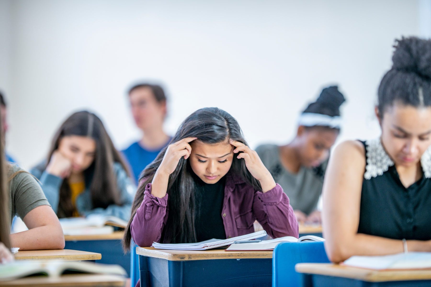 A college student sits in a classroom, looking stressed | Adjusting to College - Aspire Psychology