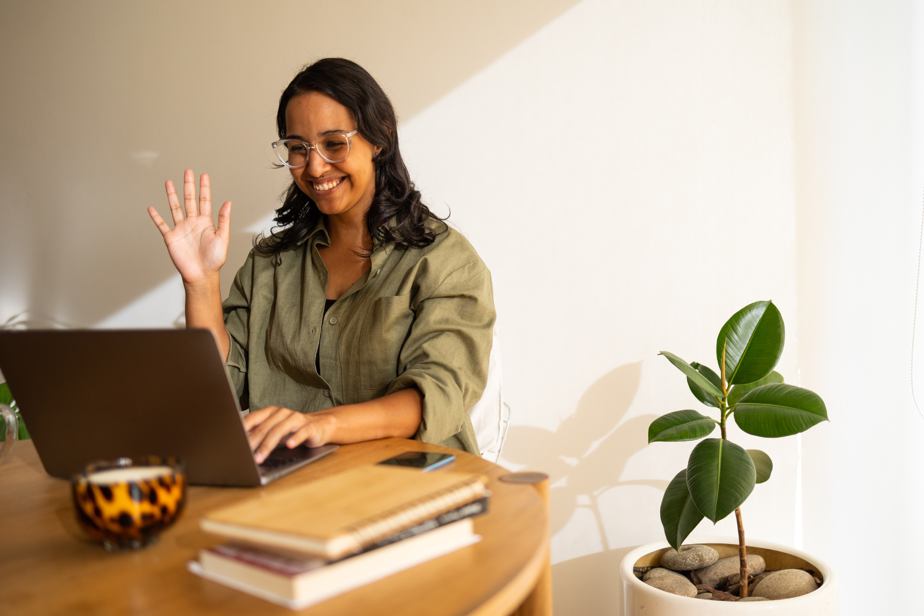 A woman waves on a video call