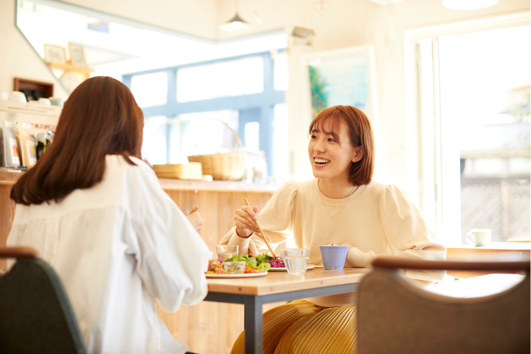 Two women sit across the table from each other, eating lunch.