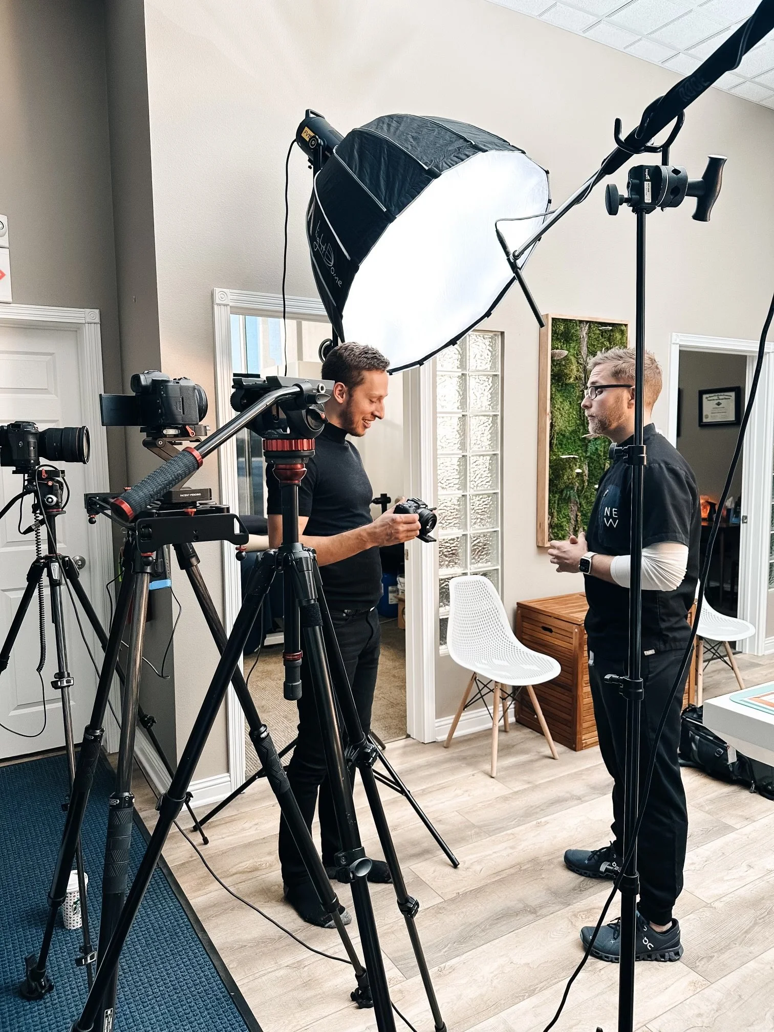 Behind-the-scenes video production with two crew members, cameras, and interview lighting.