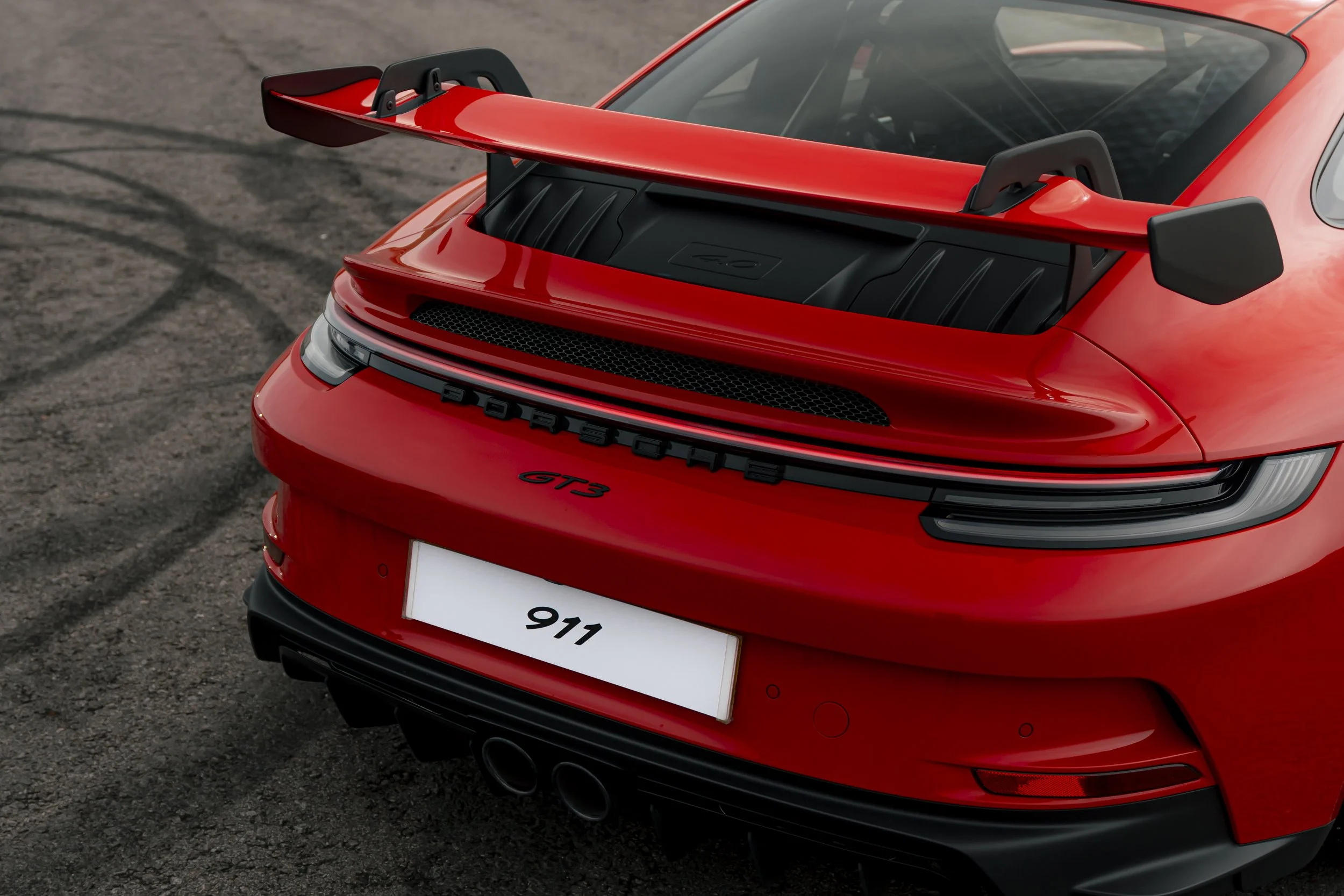 Red Porsche 911 GT3 sports car with rear spoiler parked on asphalt