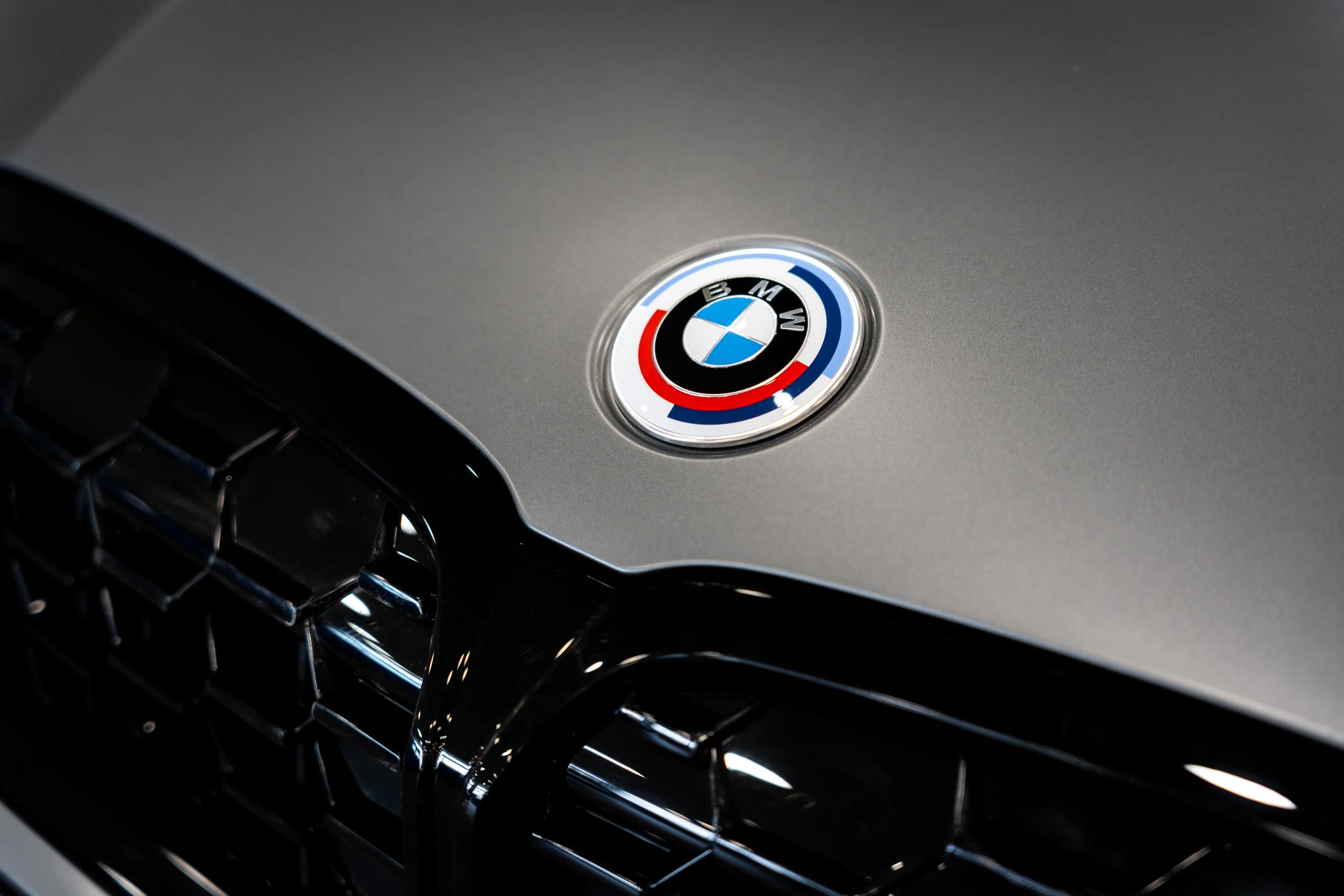 Close-up of a car's hood with a BMW badge and a black grille.