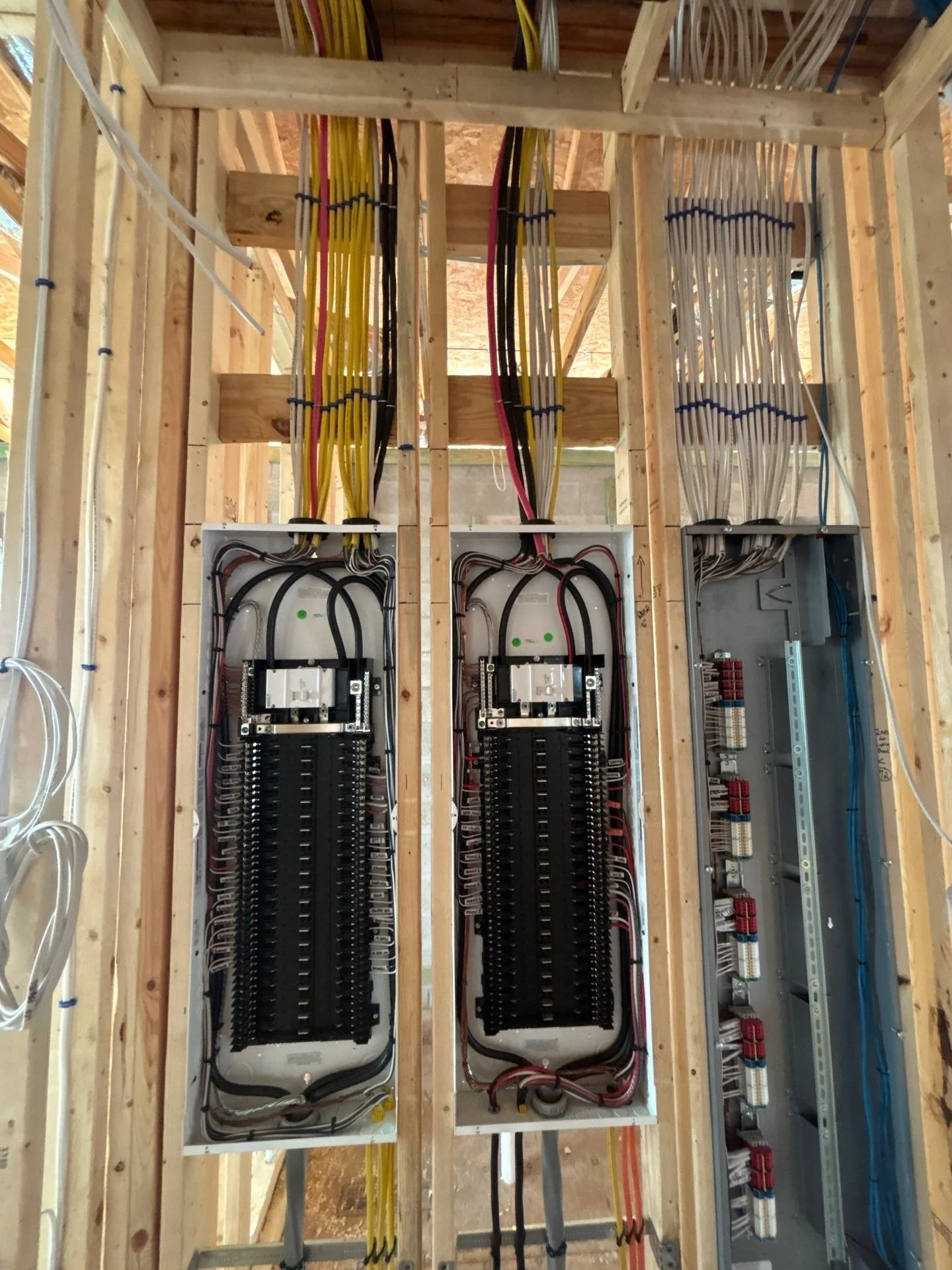 Electrical wiring and breaker panels installed in a building under construction.