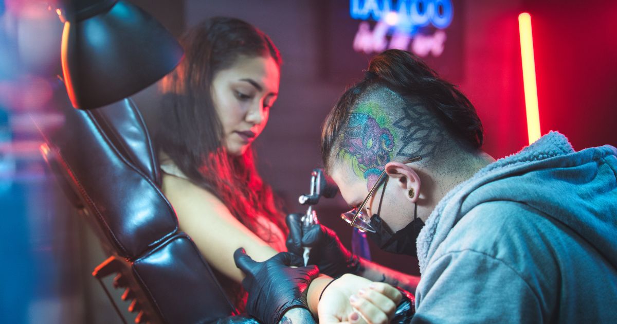 A tattoo artist creating a tattoo on a person's arm.
