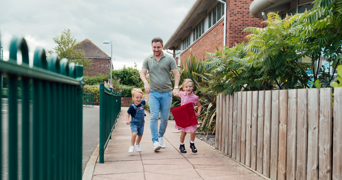 Dad walking two kids into school.