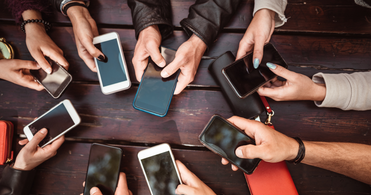 Several hands holding smartphones in a circle.