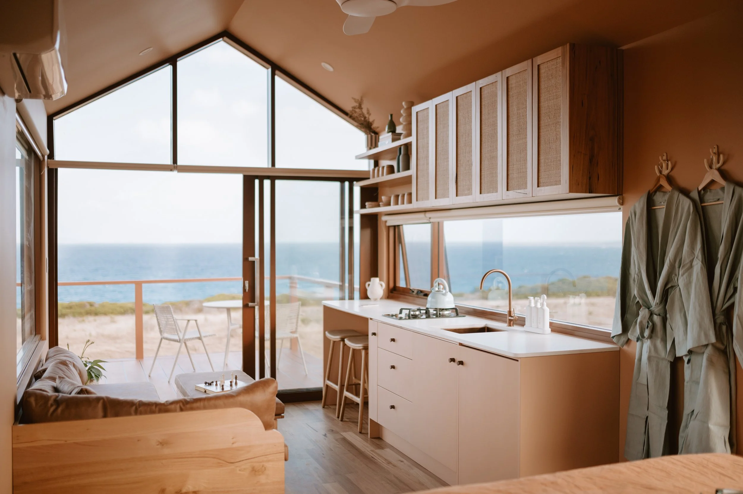 Cozy beachside cabin interior with kitchen and seating area overlooking the ocean through large windows