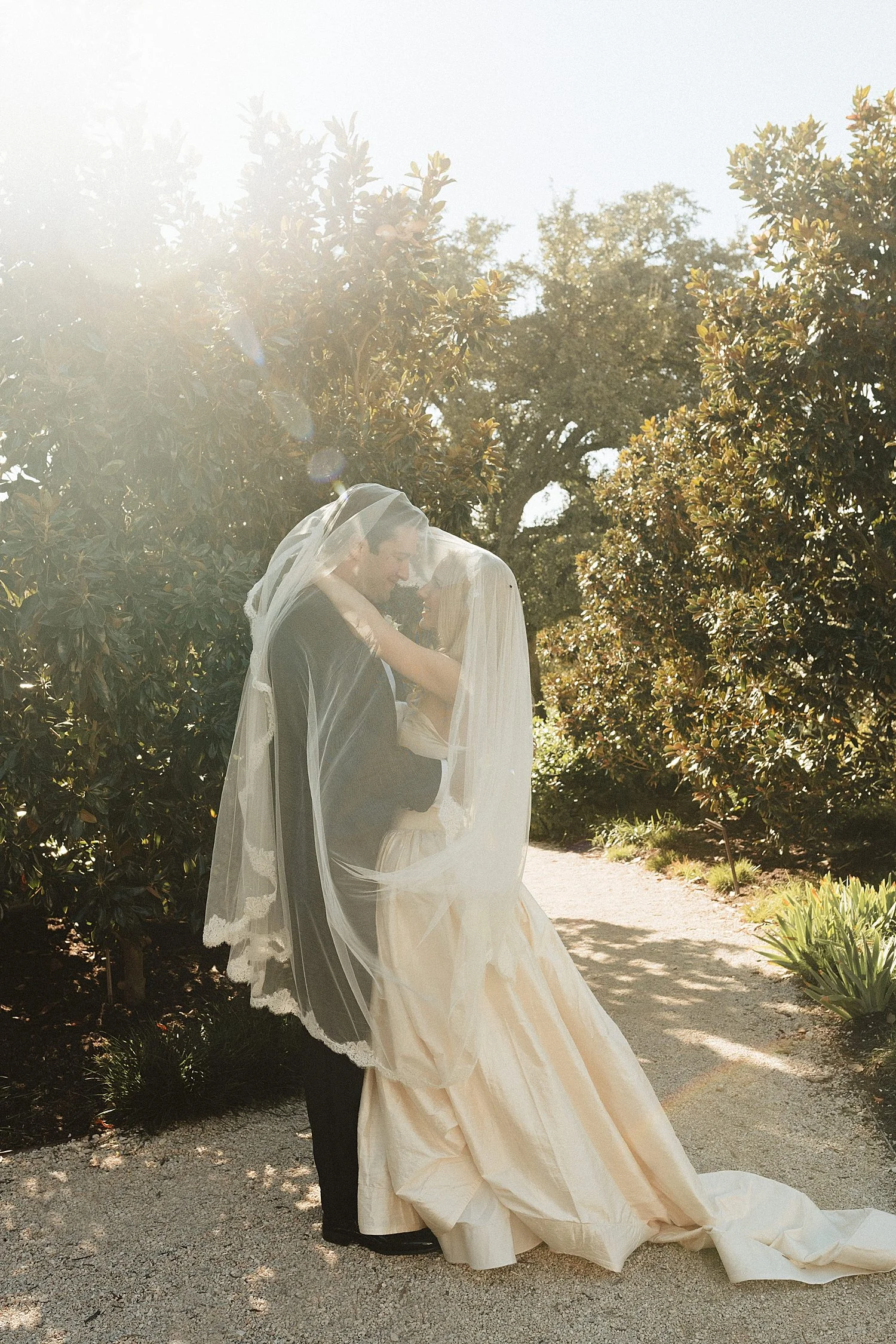 husband and wife share a kiss under veil by Jessica Joseph Photography