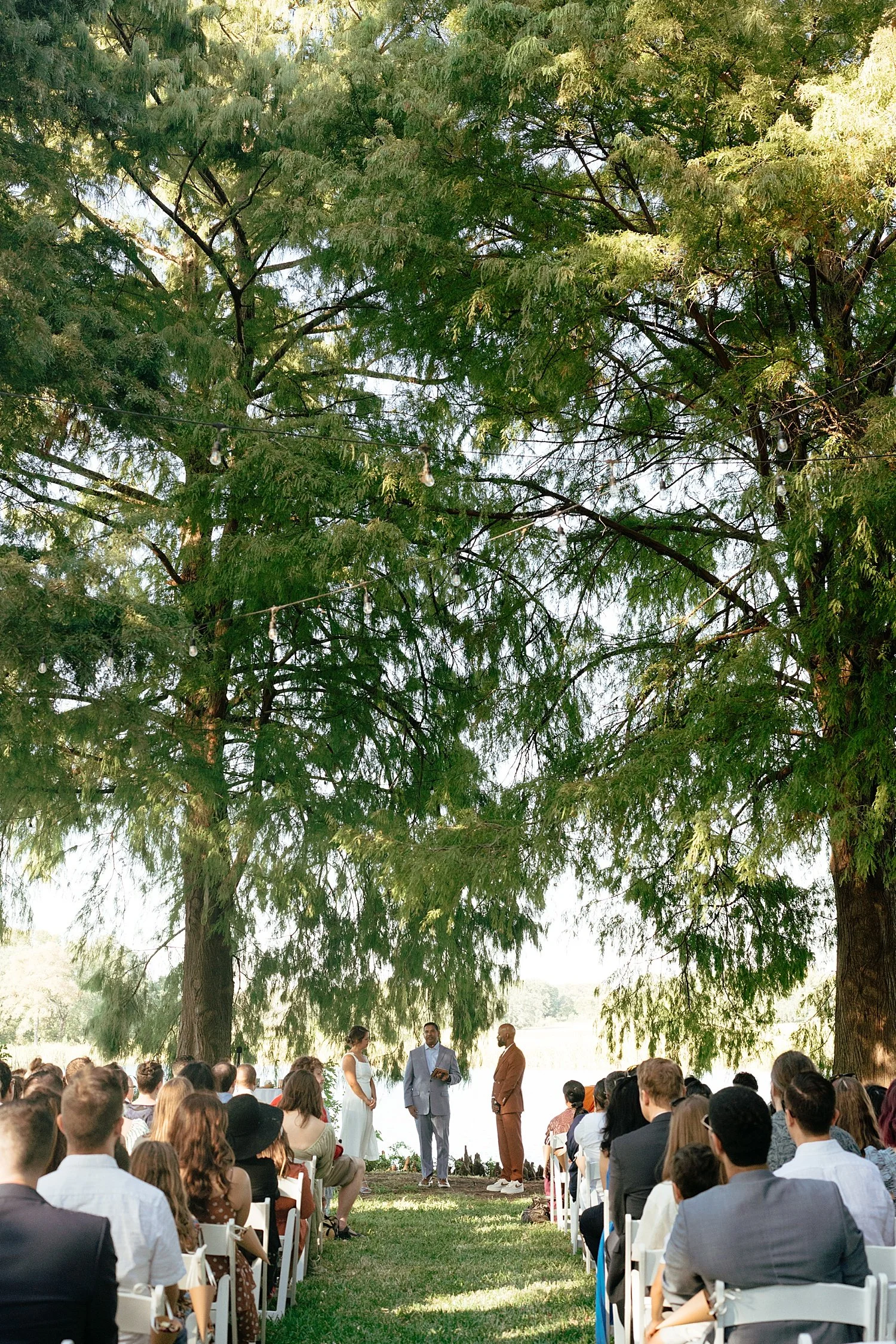  beautiful outdoor ceremony under tall trees at at Springs Lake Ranch 