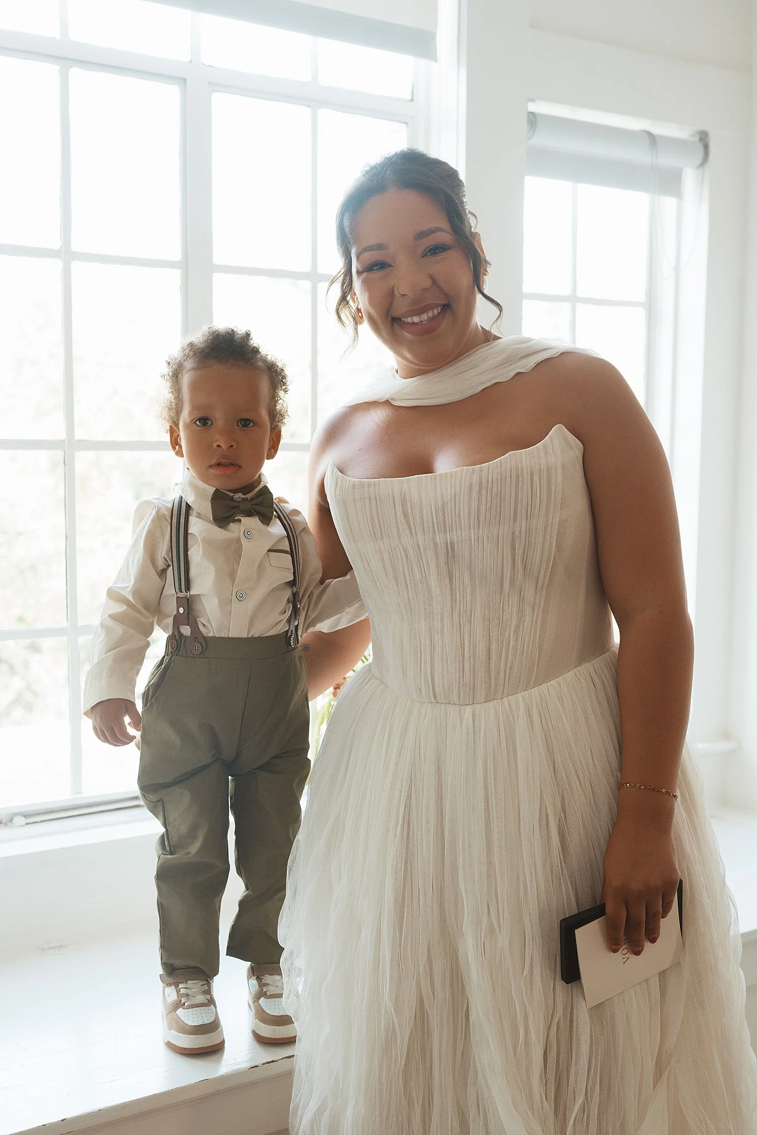  woman in white gown stands with her toddler nephew in little suit by Jessica Joseph Photography 