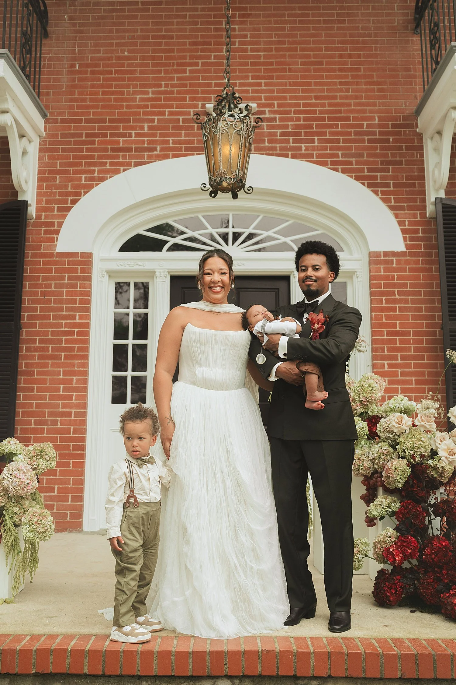  man and woman stand on impressive front porch with two small children by Austin wedding photographer 
