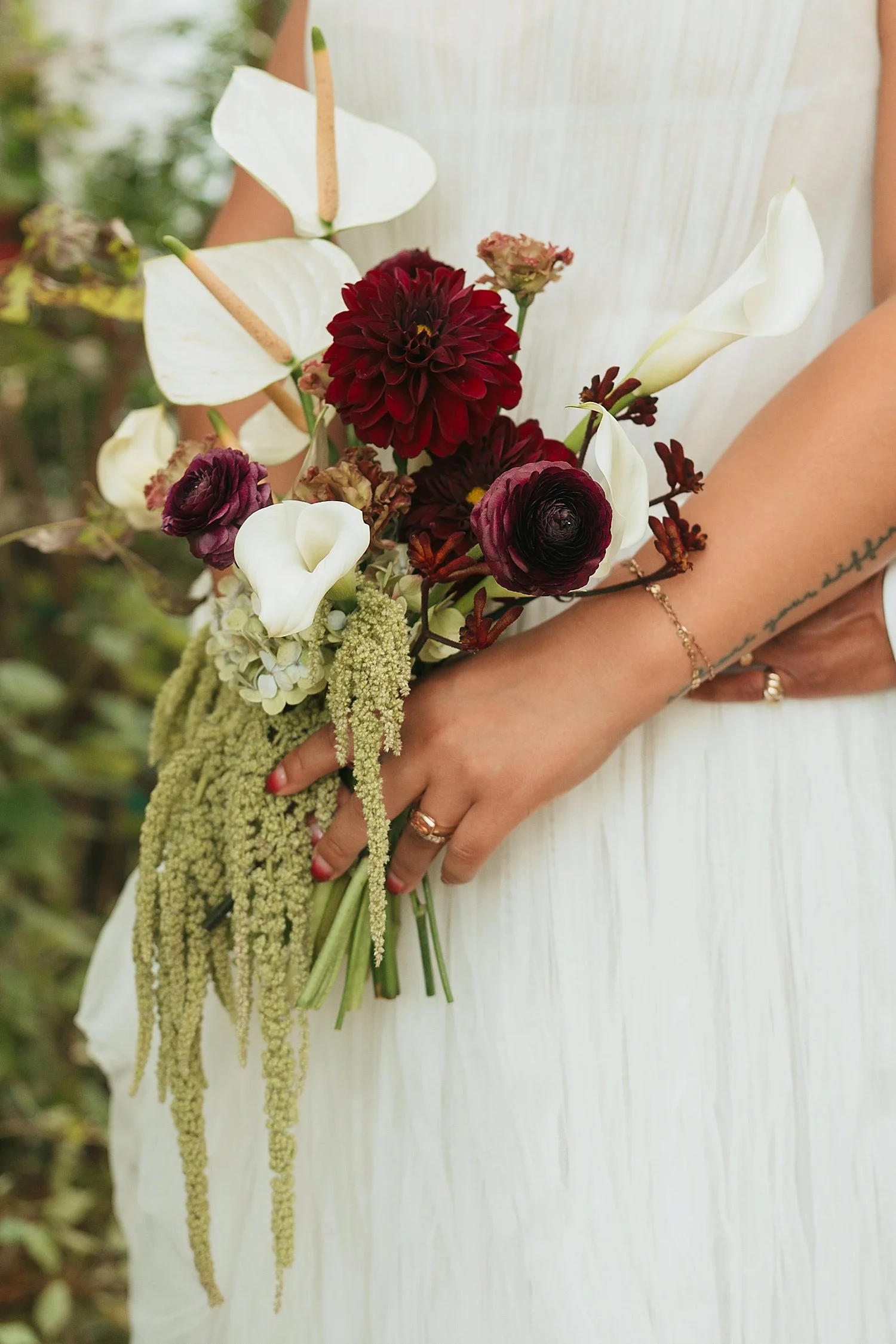  bride holds up her cascading bouquet of white and maroon flowers by Austin wedding photographer 