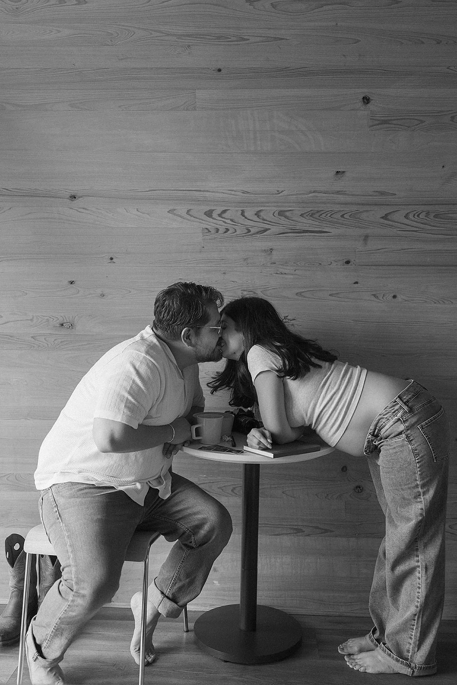  mom and dad with expecting belly lean over table for kiss by Jessica Joseph Photography 