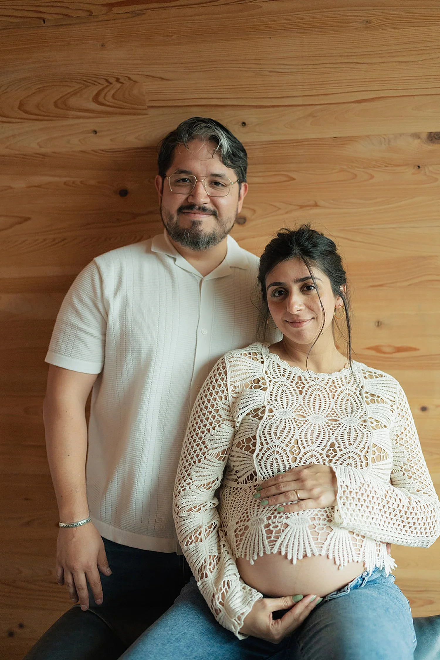  man and woman sit in front of wood paneling by Austin maternity photographer 