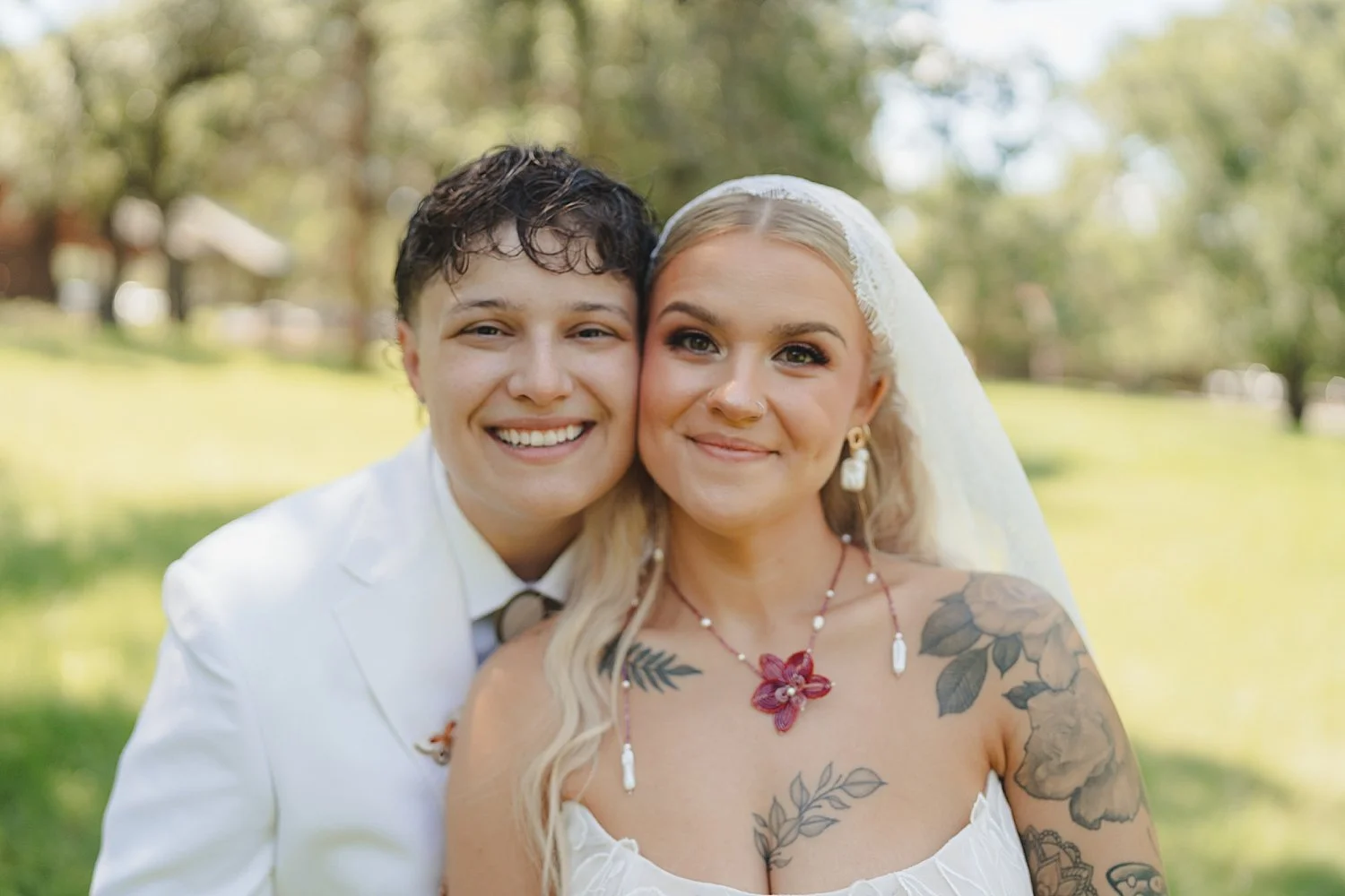  brides with tattoos on lawn of venue for colorful wedding celebration 