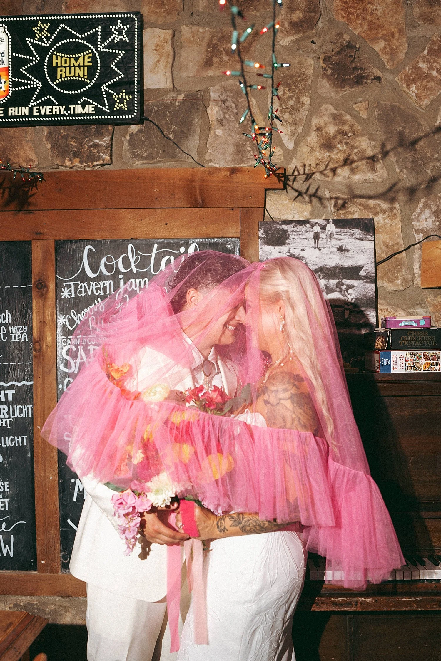  newlyweds kiss under bright pink veil at colorful wedding celebration 