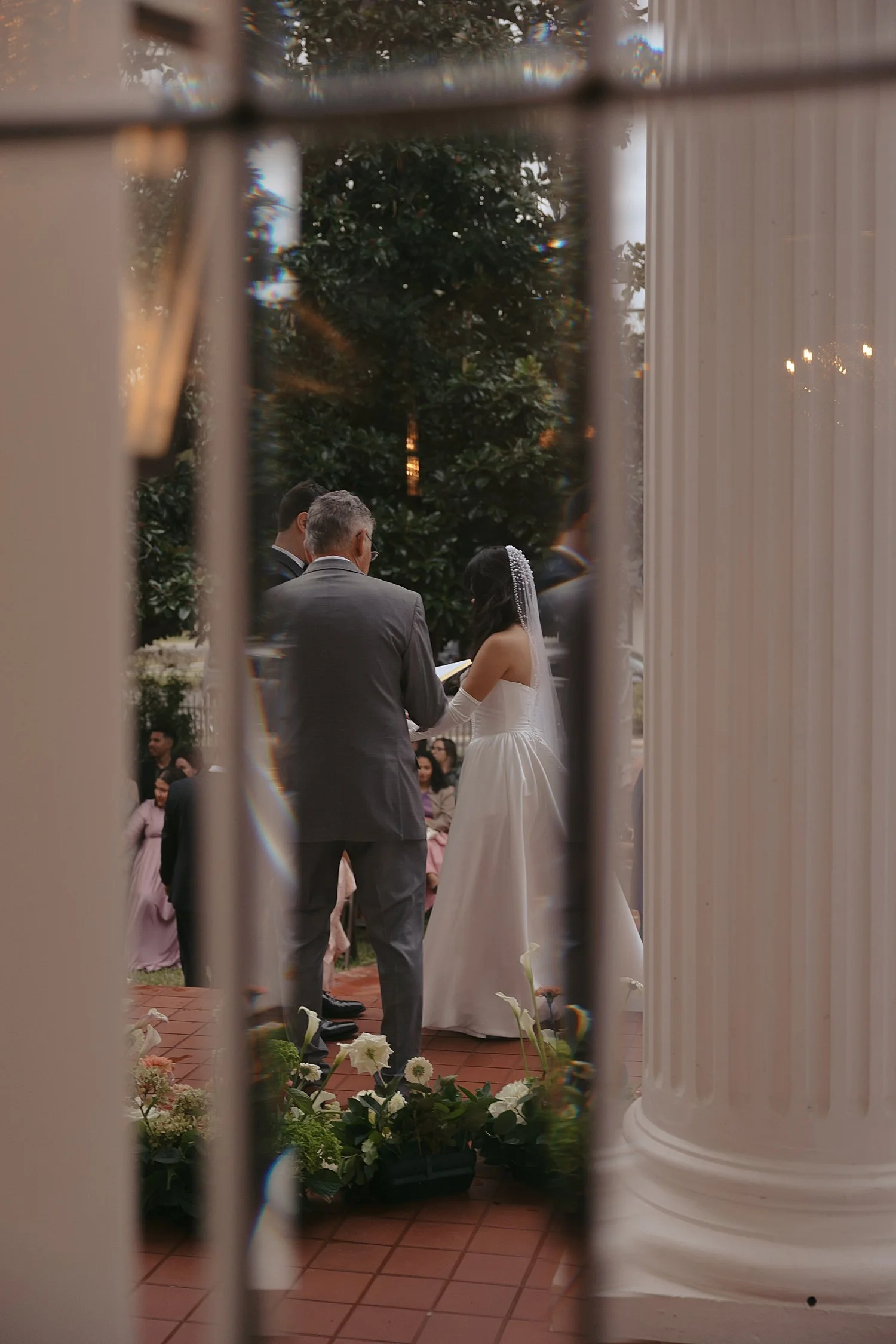  newlyweds on the other side of a window during their ceremony at Woodbine Mansion 