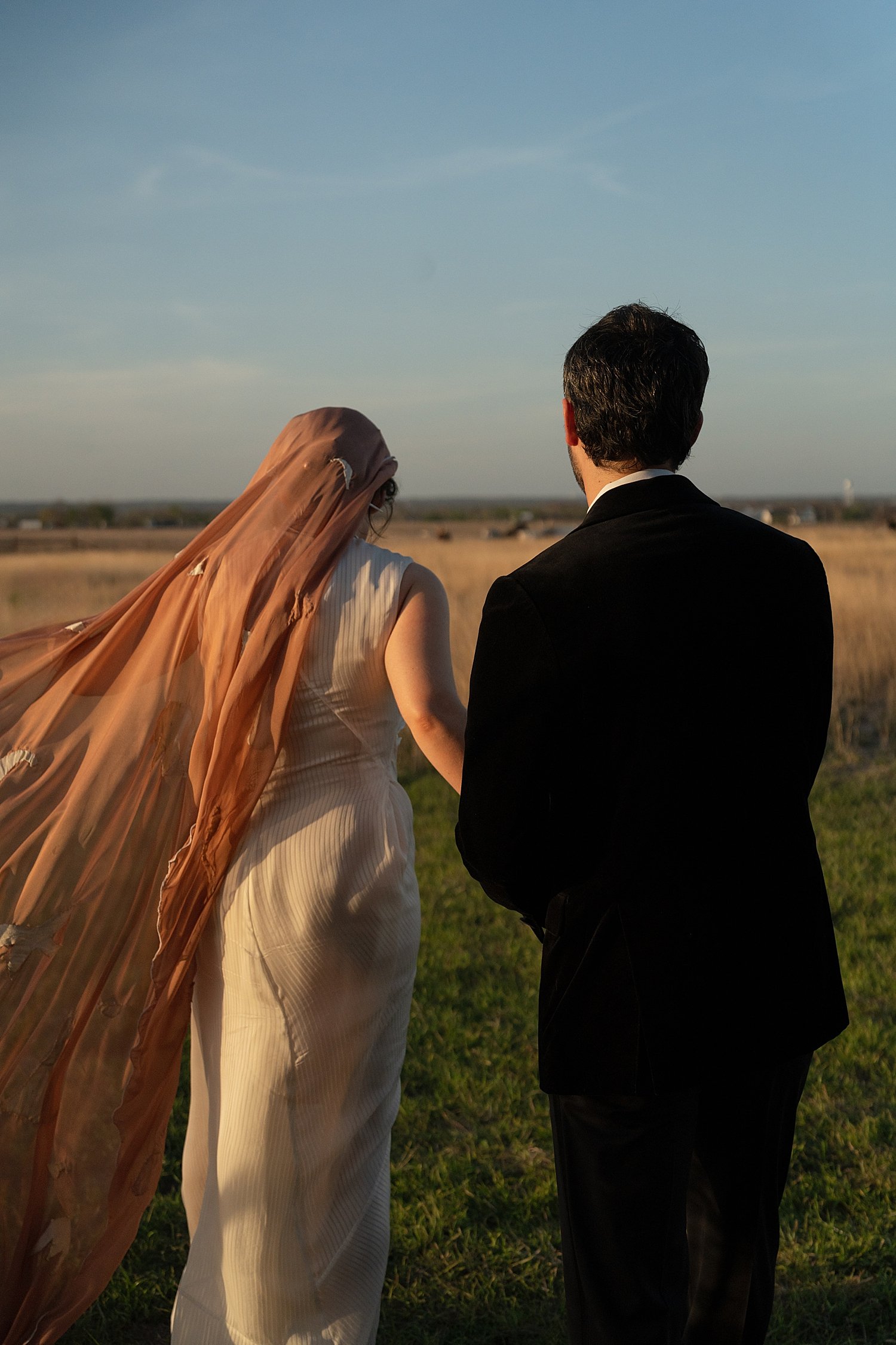  Newlyweds walk across field during sunset by Austin photographer 