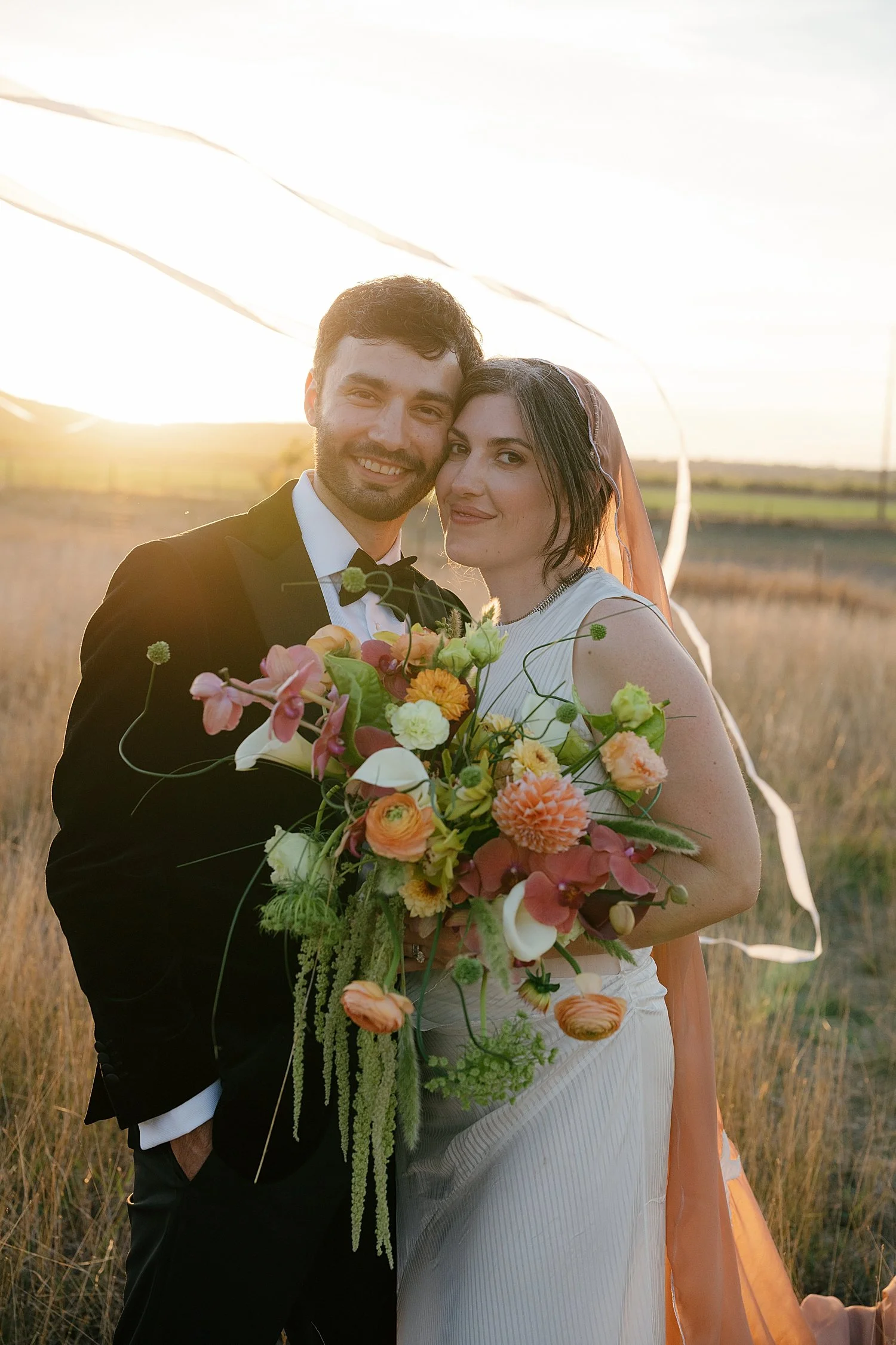  husband and wife stand in golden hour light with ribbons around them by Austin photographer 