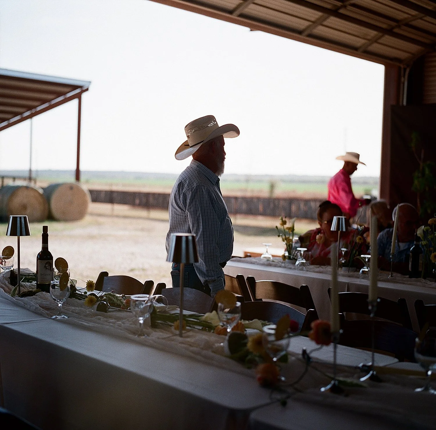  guest stands next to buffet at barn reception at backyard wedding in Texas Hill Country 