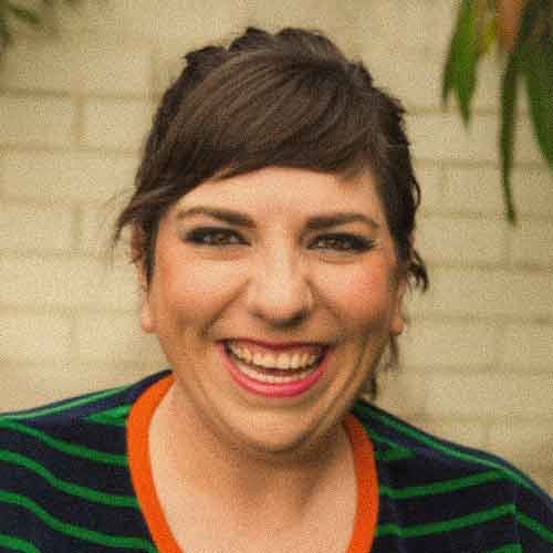 Maeve Marsden, the creative director at Varuna The Nationals Writers' House. She has a wide open smile, short dark hair, and is wearing a striped shirt with green, orange, and black colours.