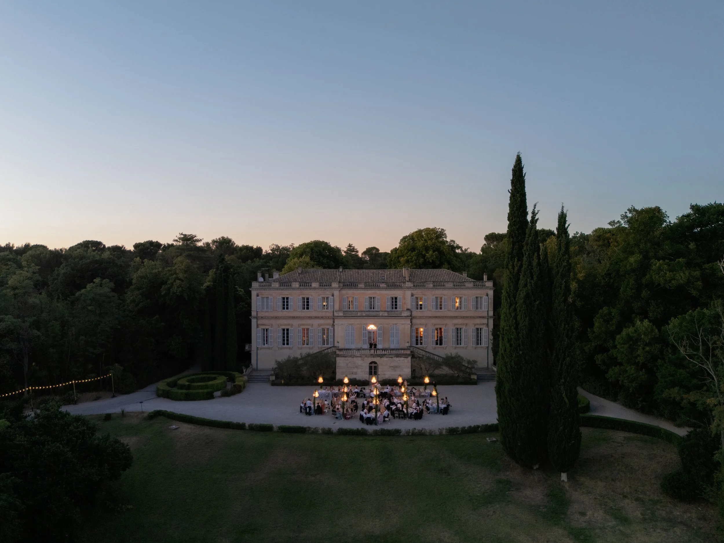 wedding dinner at a French Chateau in the south of Franc, nighttime shot by drone showcasing the beautiful tables and chandeliers. Planned by professional UK wedding planner.