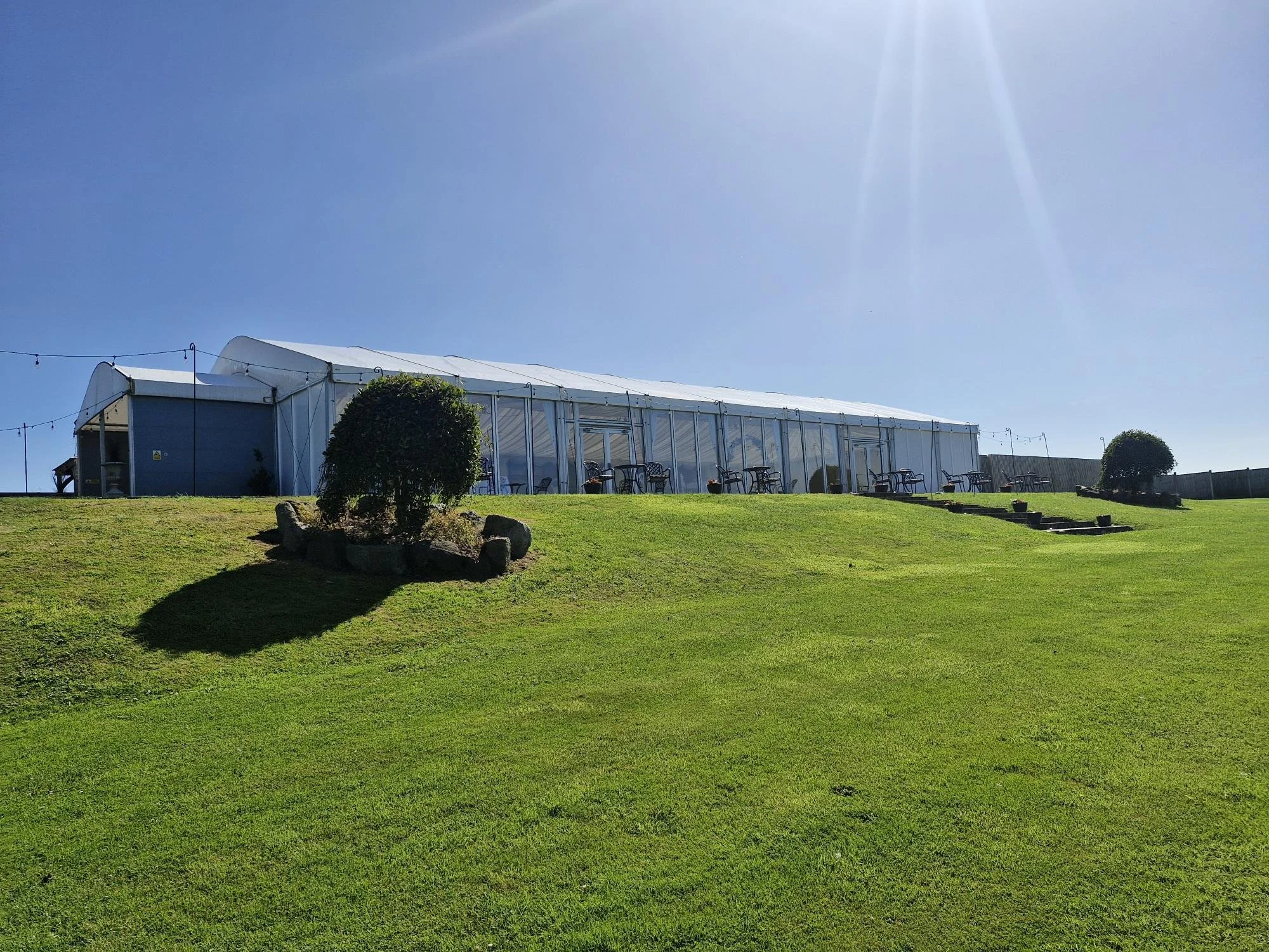 large event marquee on grassy hill with clear sky