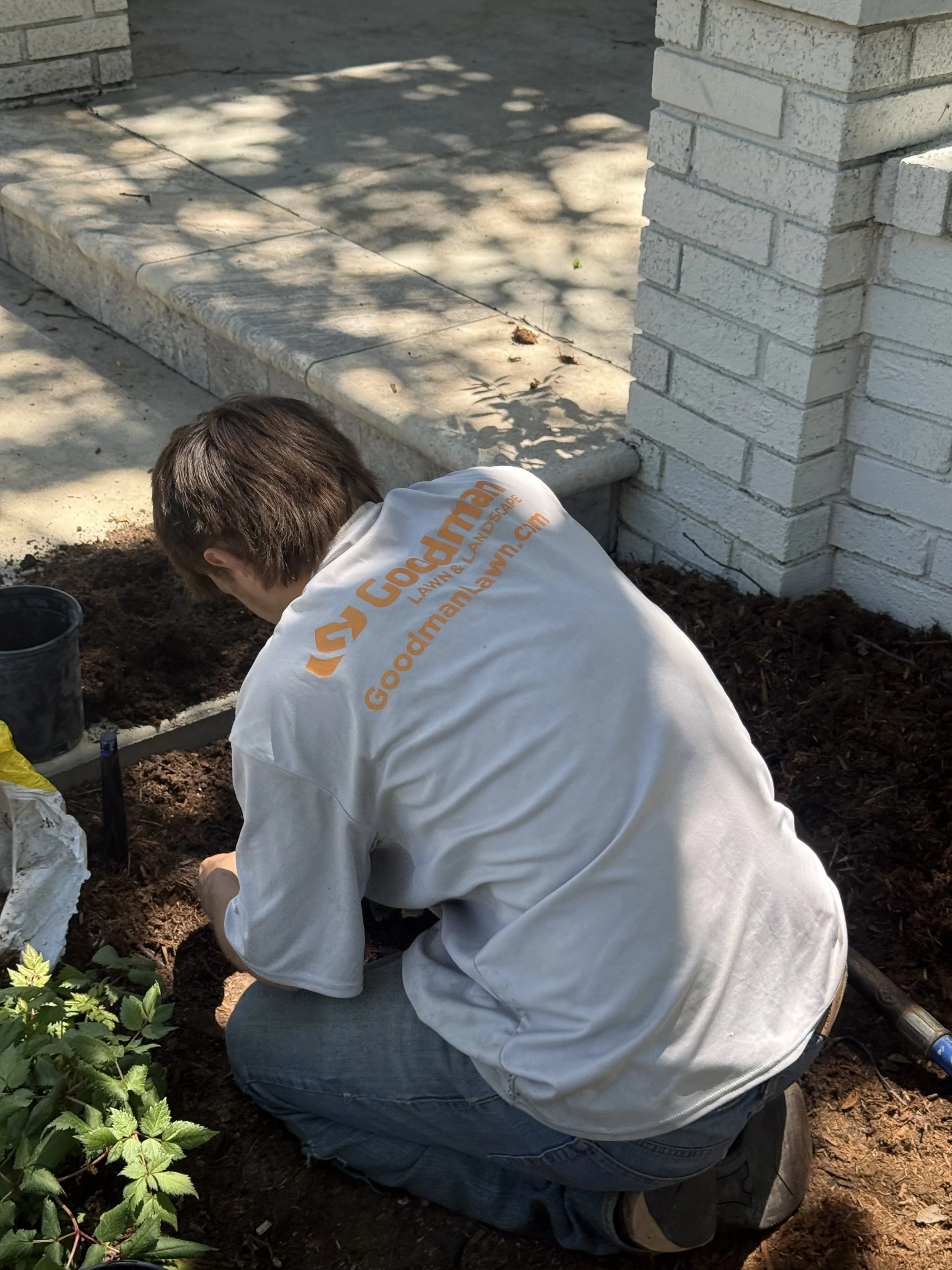 a person planting flowers in a garden bed in wichita kansas