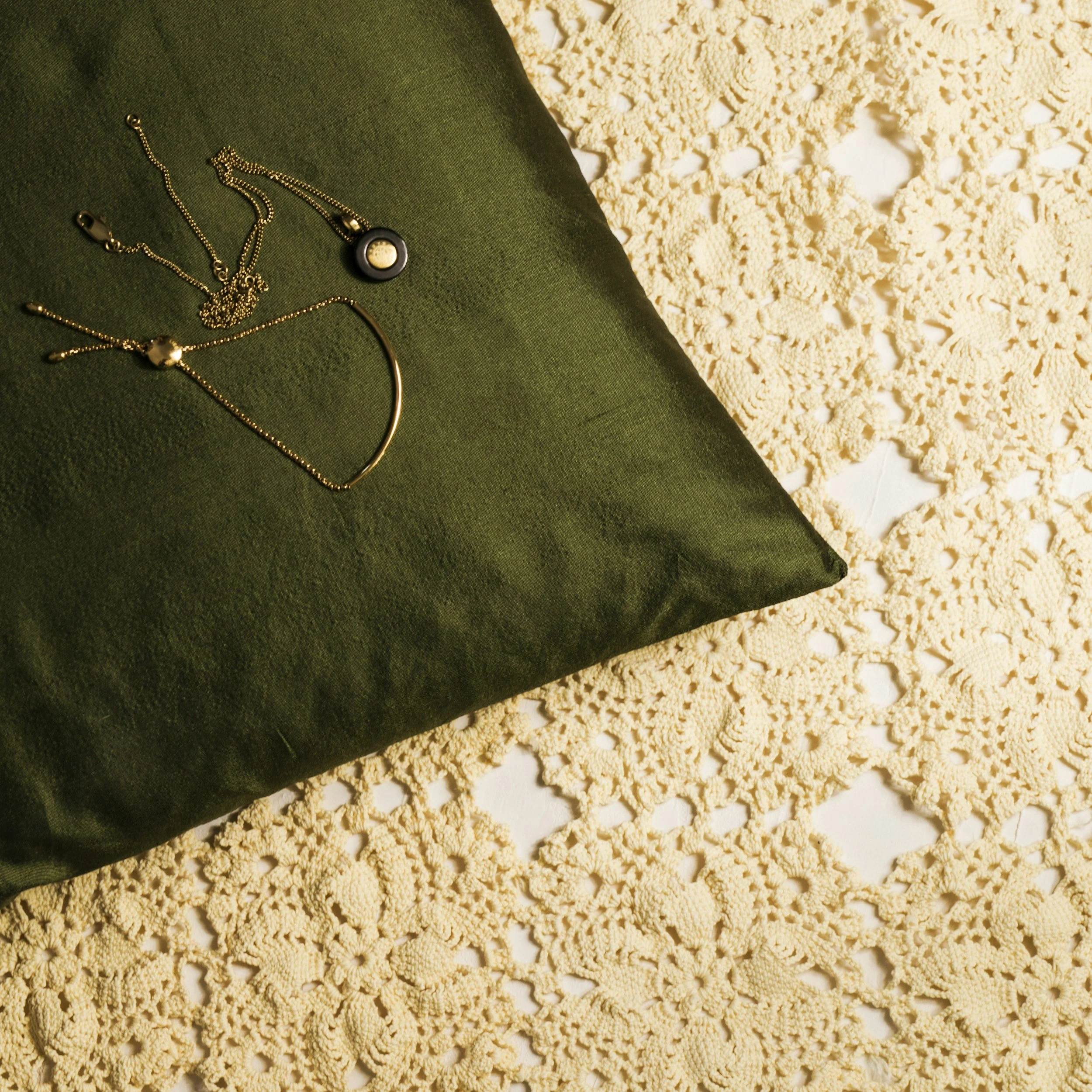 Necklaces on a green cloth and cream-colored lace doily.