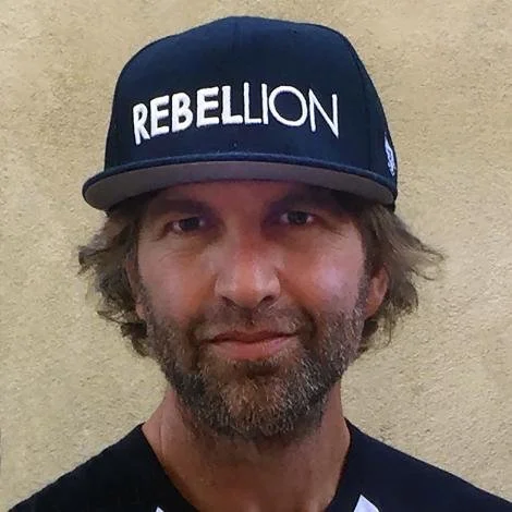 Man wearing a black cap with the word 'REBELLION' in white letters.