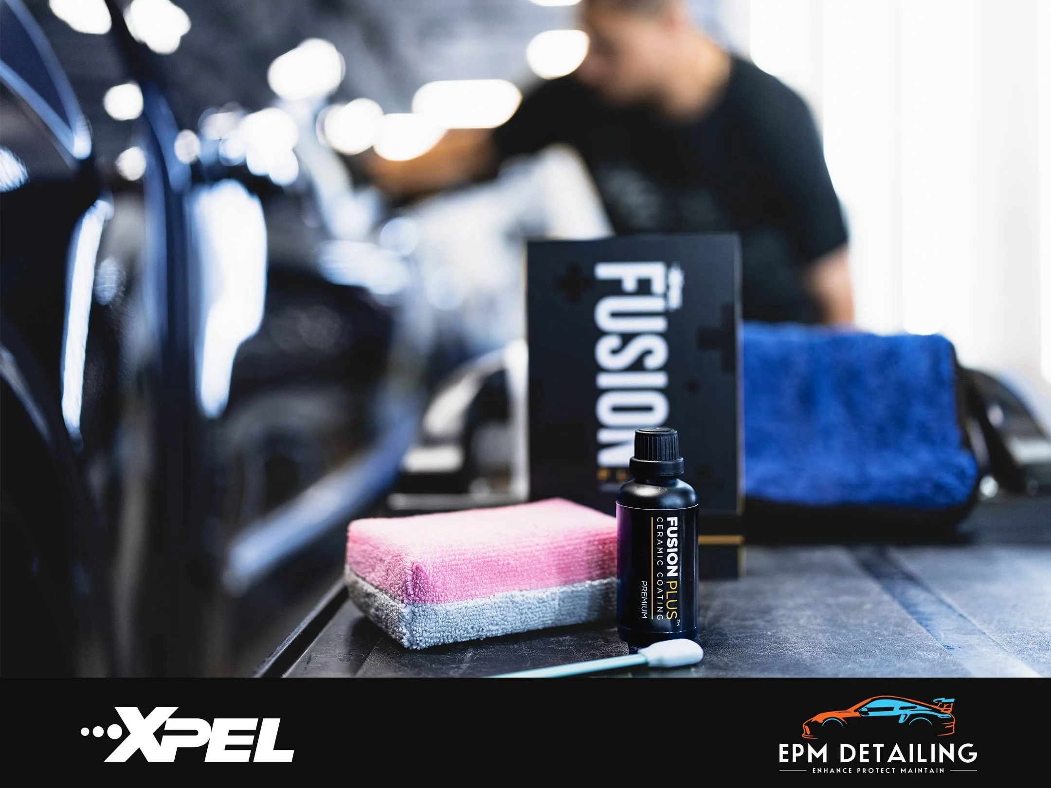 EPM Detailing XPEL FUSION PLUS Ceramic Coating Package: Coating bottle, swab, applicator, and packaging on table with a blurred background of a man polishing a black car.