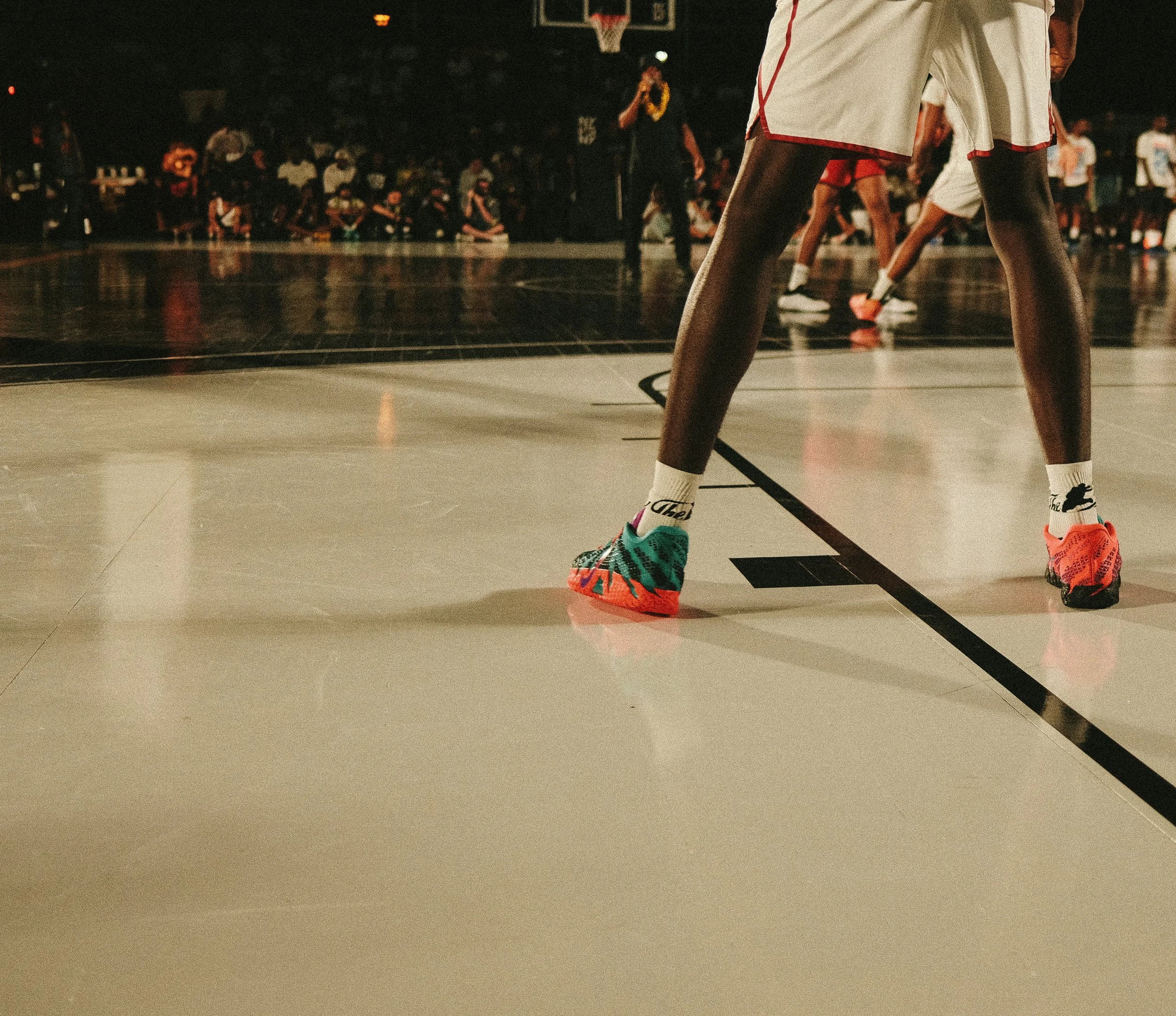 Close-up of a basketball player standing at the free throw line wearing colorful basketball shoes during a game.