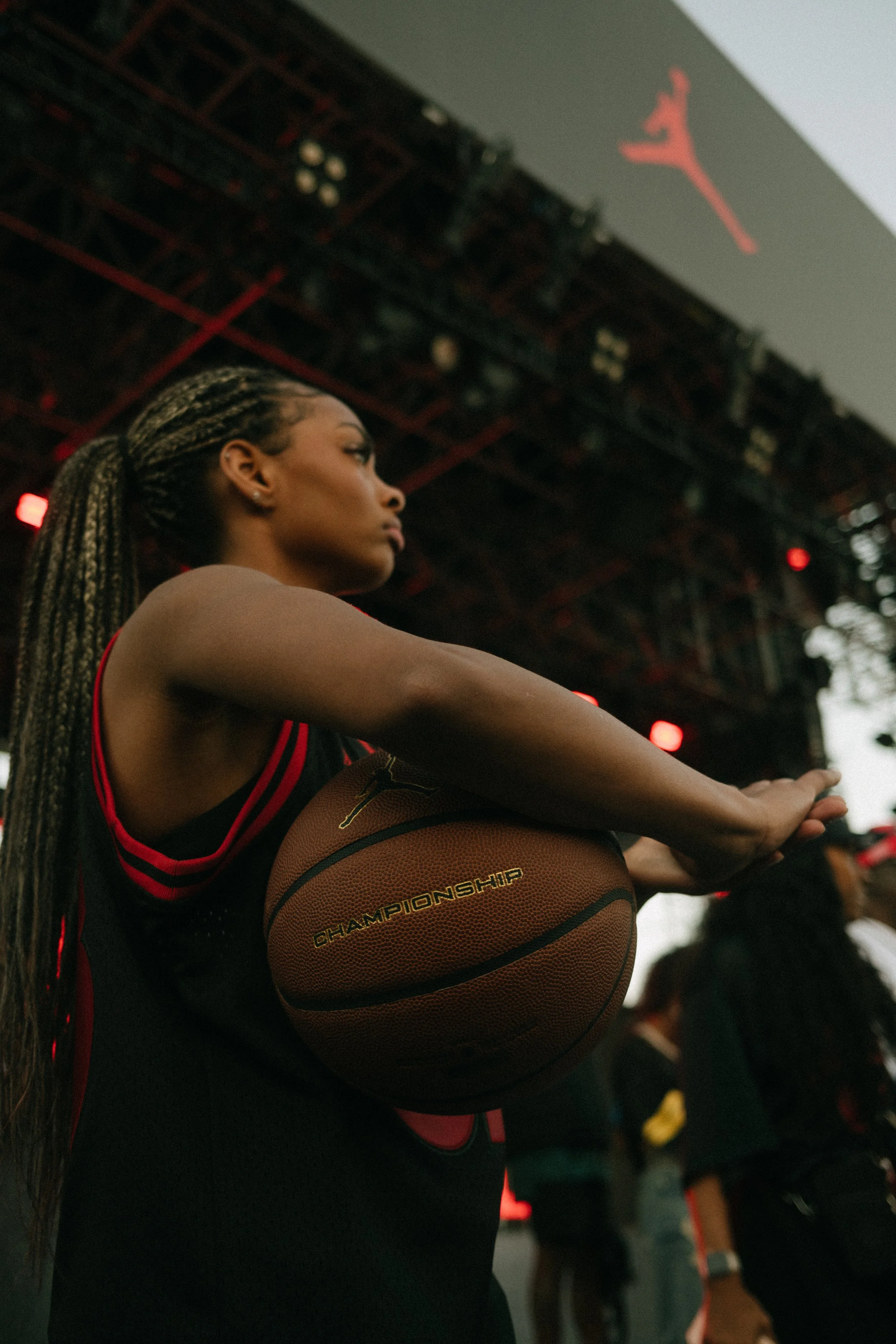 A female basketball player with long braids holding a basketball during a game or practice.