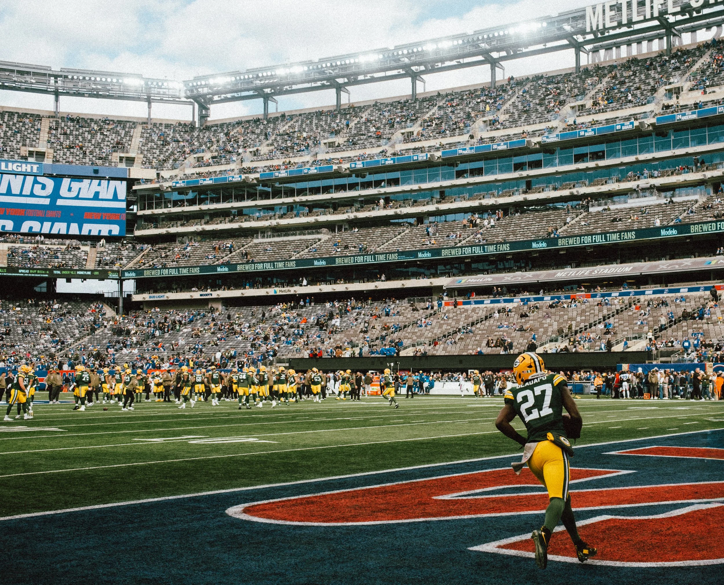 Green Bay Packers football player number 27 running on the field during a game at MetLife Stadium with fans in the stands.