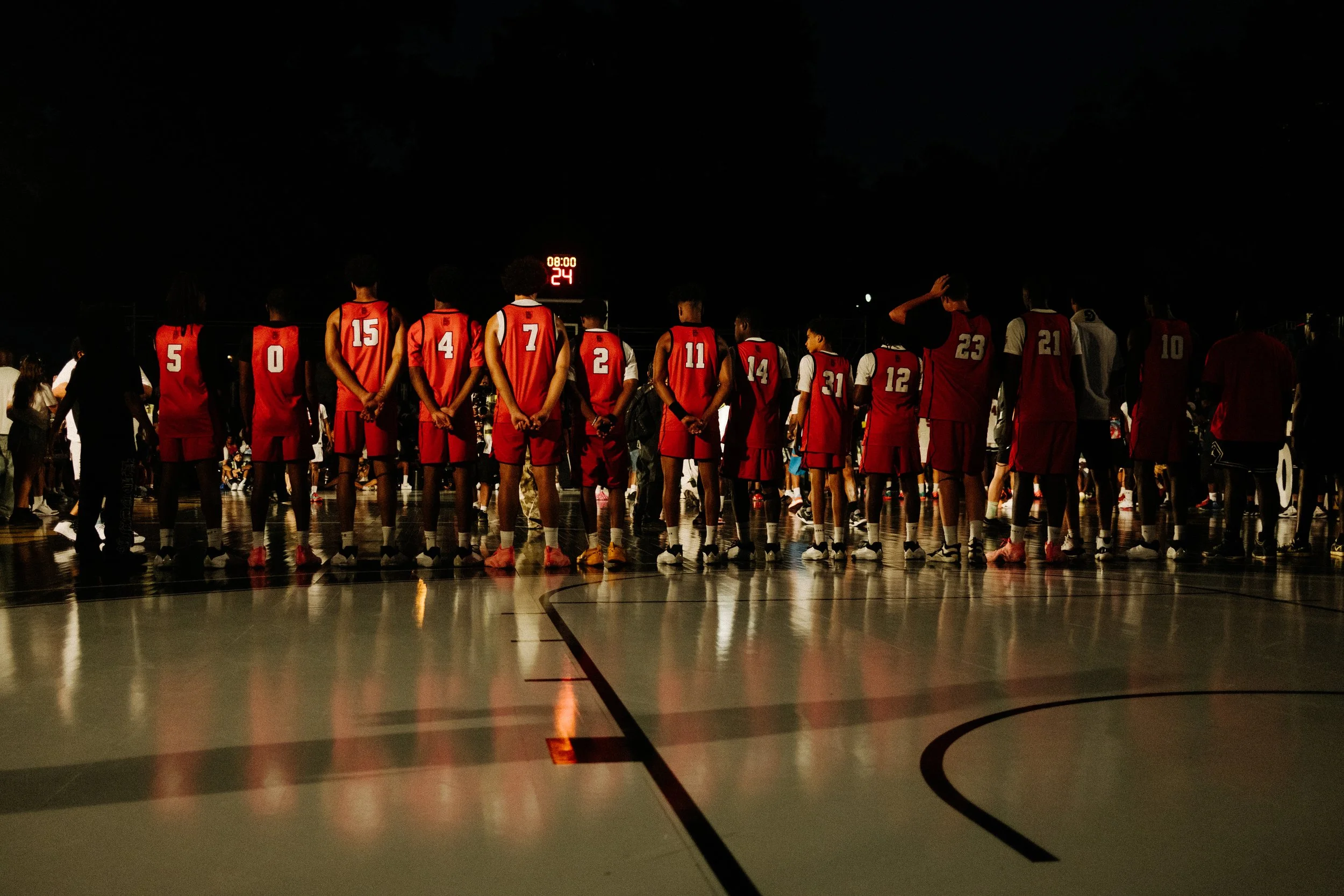 A basketball team standing in a line during a night game or event.